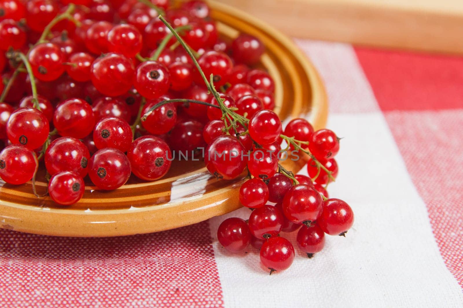 Berries of a red currant in a plate on a table