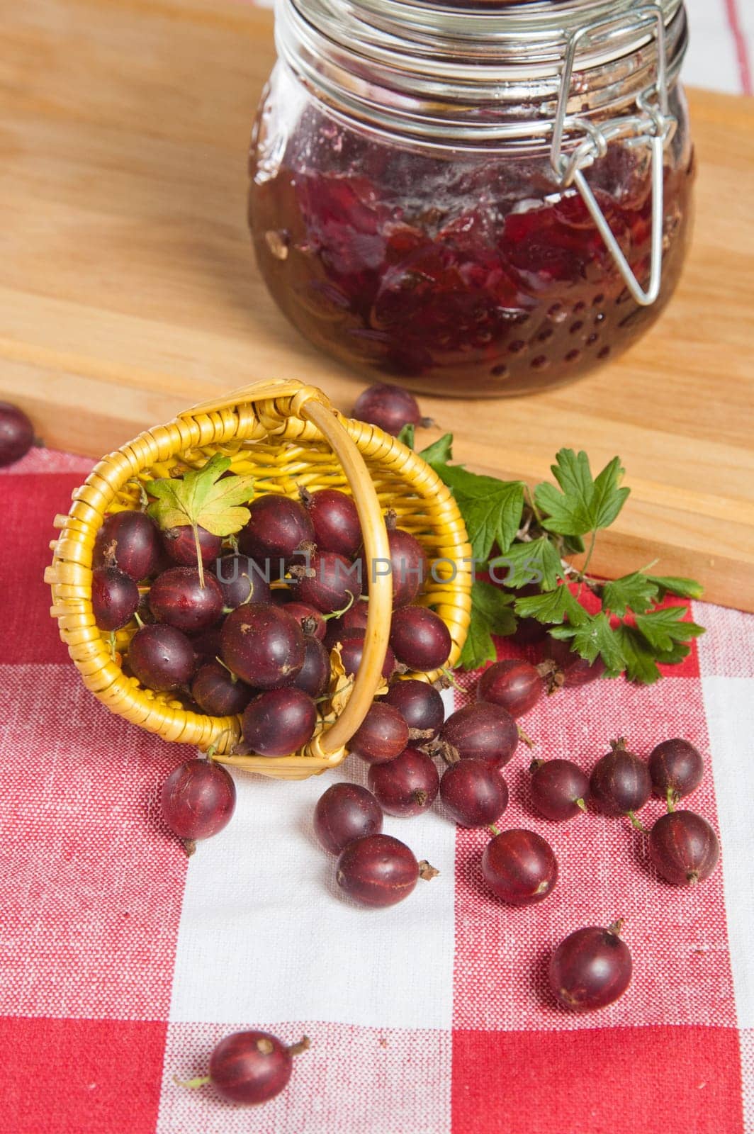 Basket with berries of a red gooseberry and jam