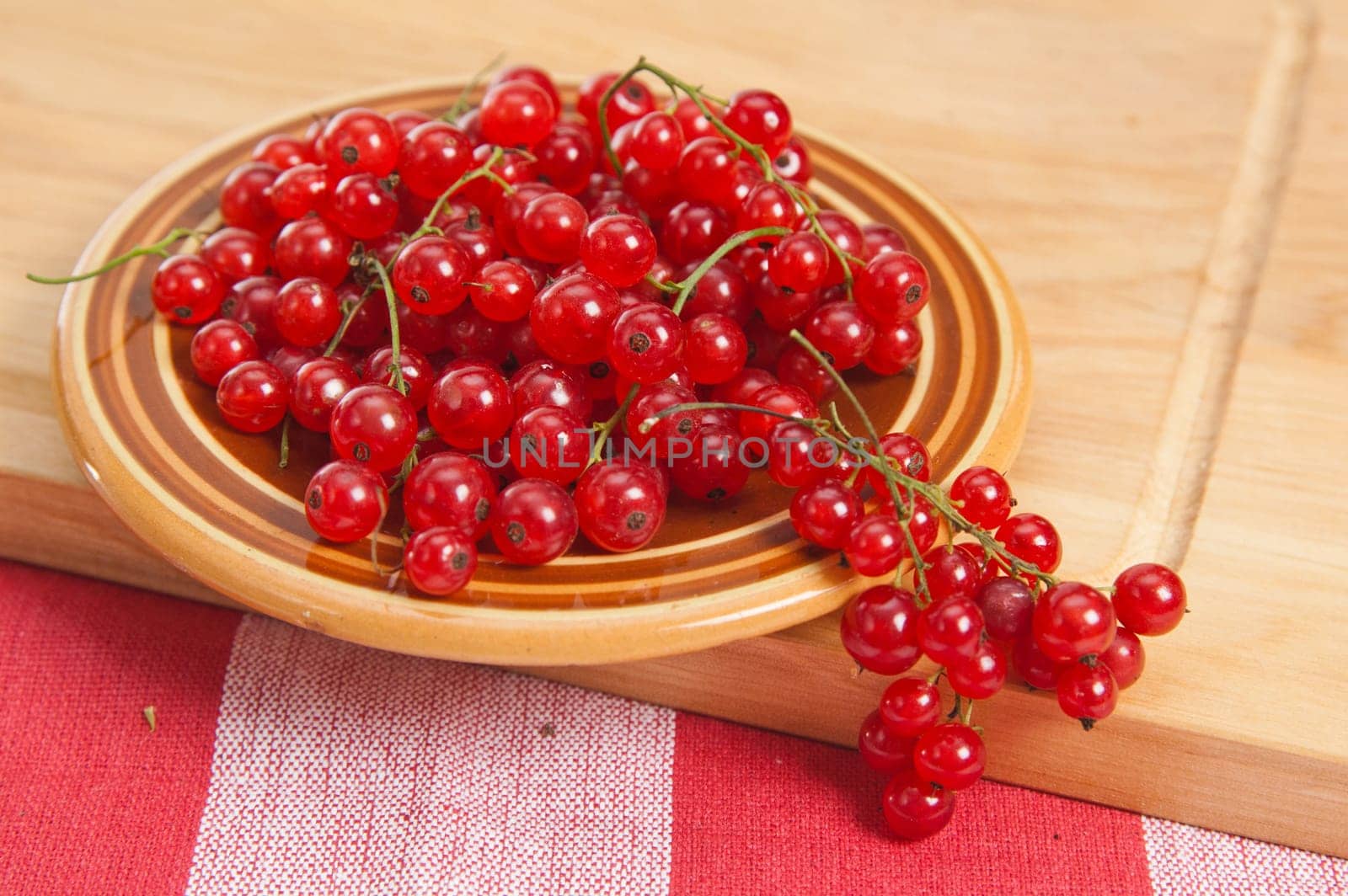 Berries of a red currant in a plate on a table