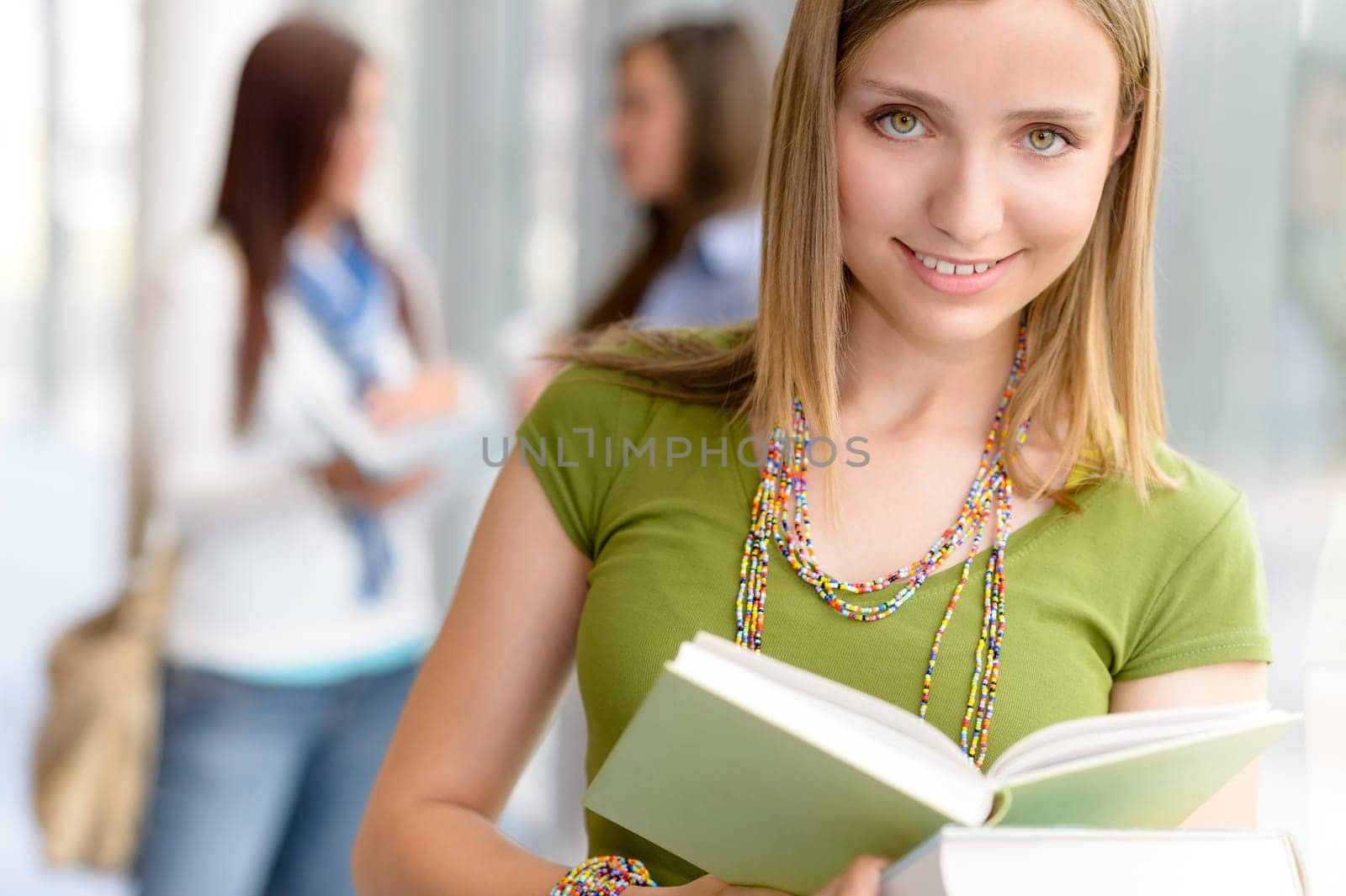 Female student reading book at high school library hall