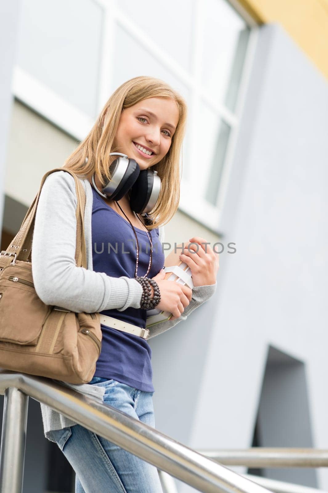 Young student woman leaving school building holding books smiling outdoor