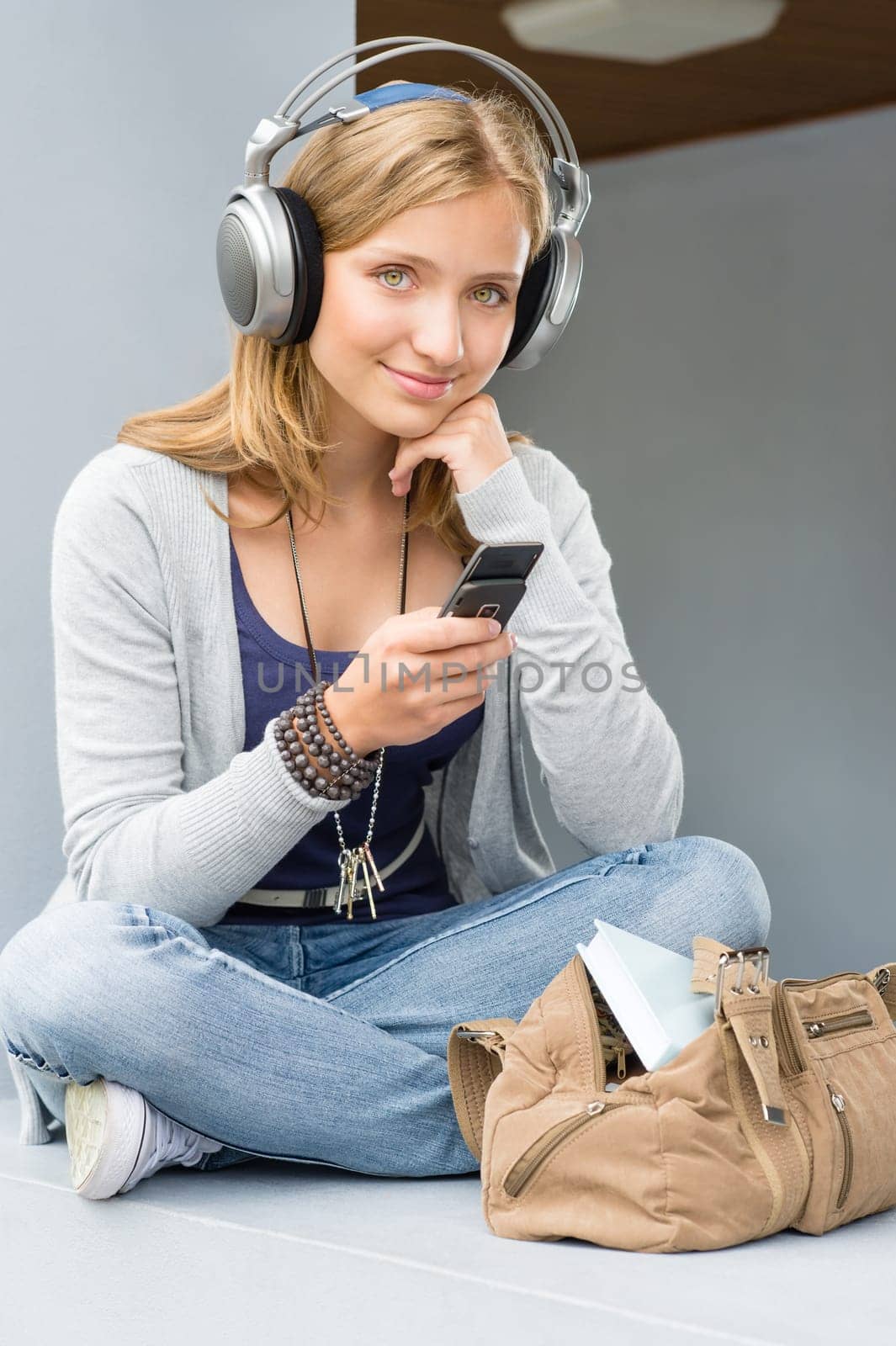 Young woman holding her mobile phone sitting wall outdoor