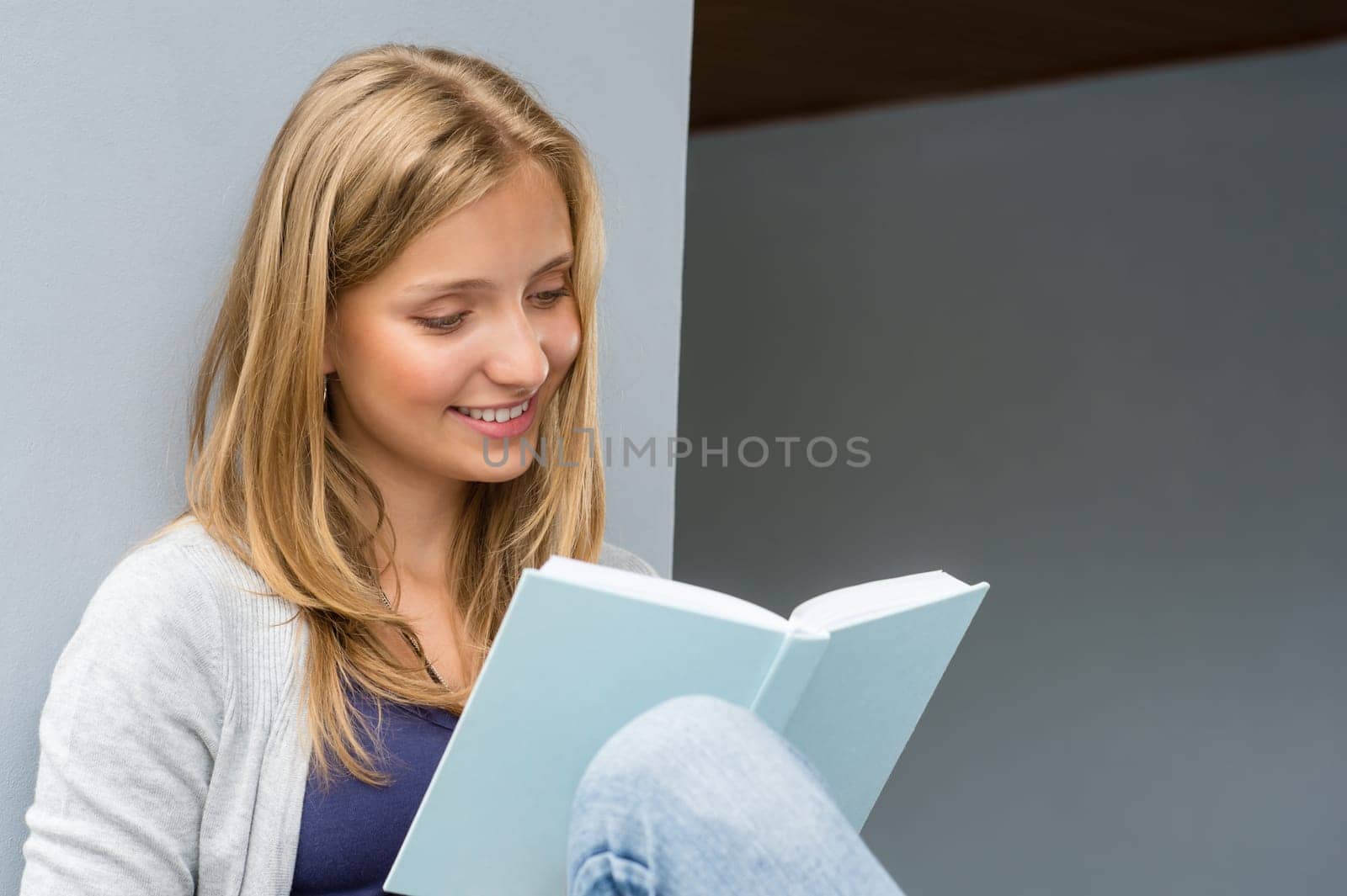 Student girl reading book sitting outside smiling