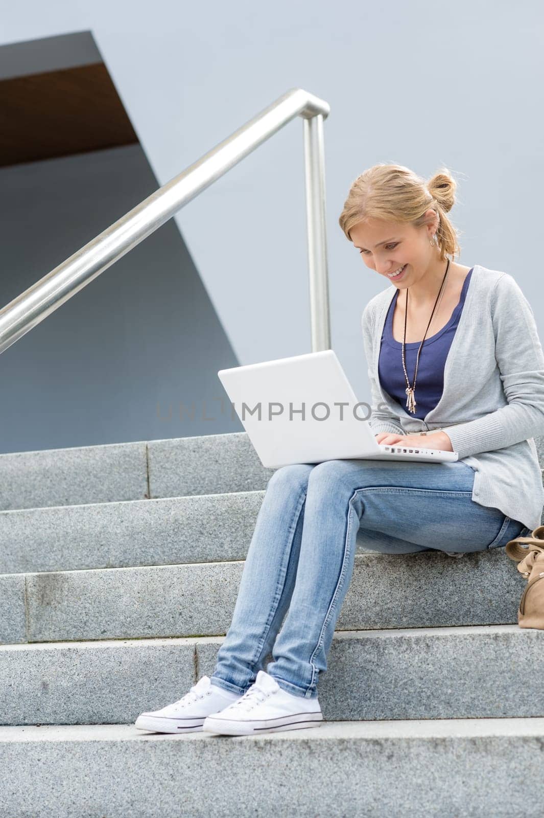 Student girl on stairs with laptop computer smiling outdoor