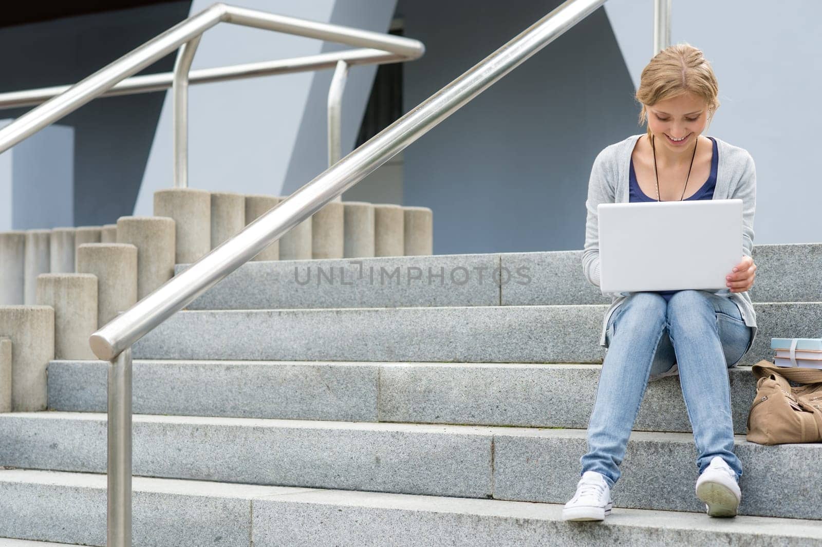 Teenage girl working on laptop computer happy student on stairs