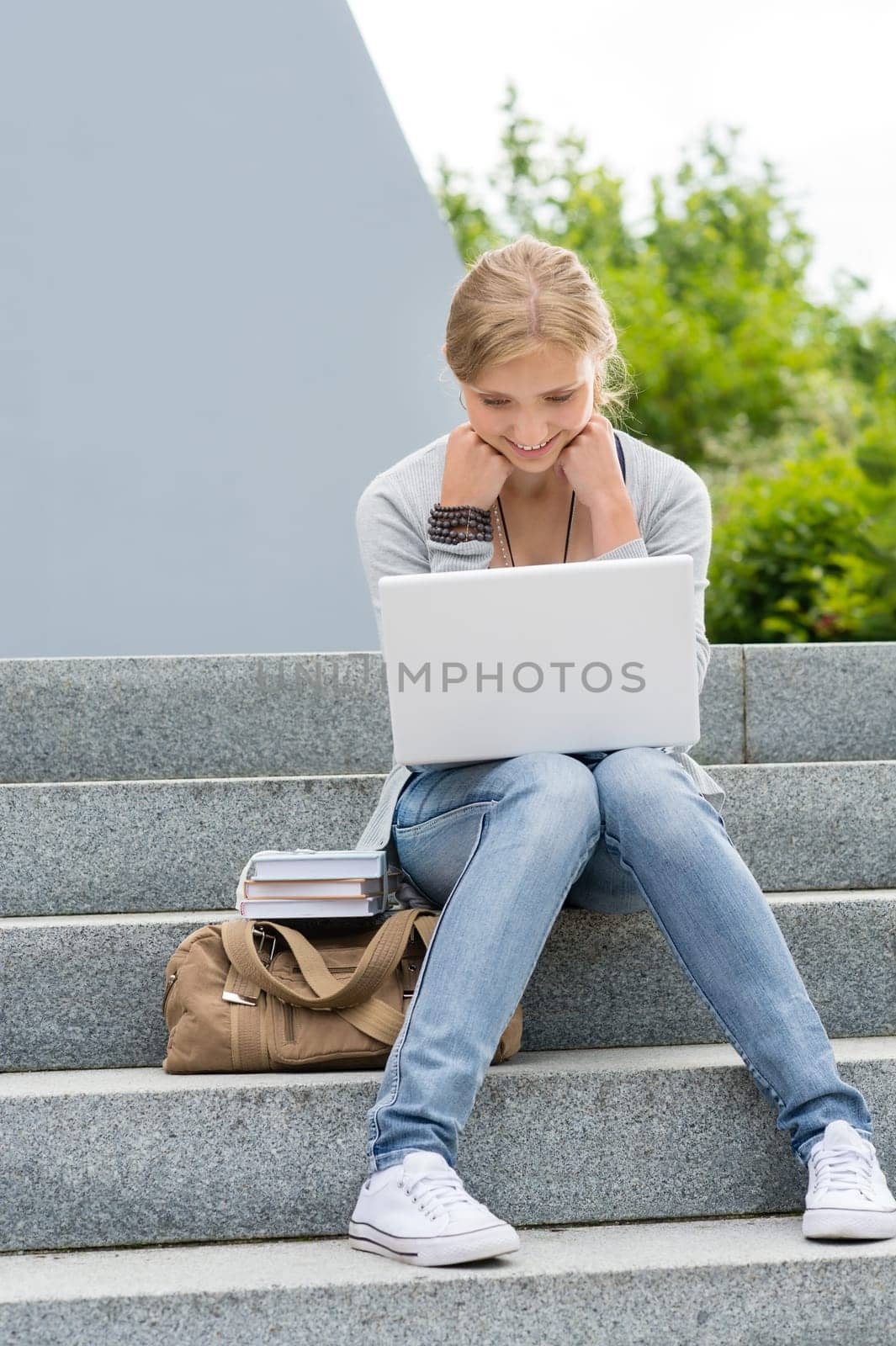 Young student woman outdoor with laptop sitting on stairs