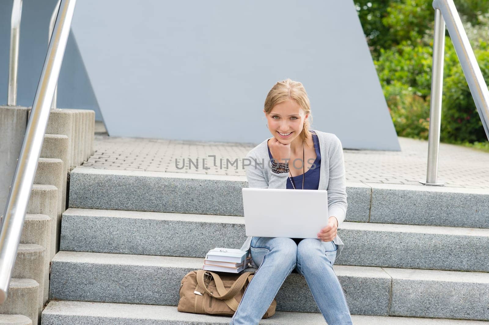 Young student woman sitting on university steps happy teenager outdoor