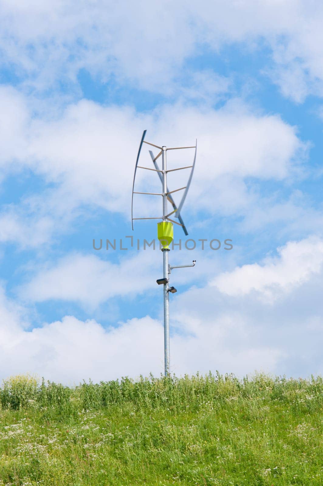 small vertical axis wind turbine on a green hill
