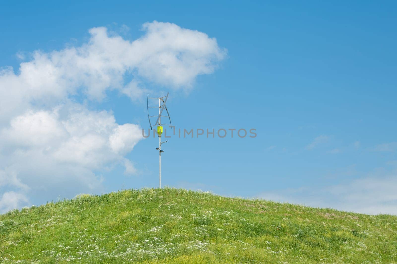 small vertical axis wind turbine on a green hill