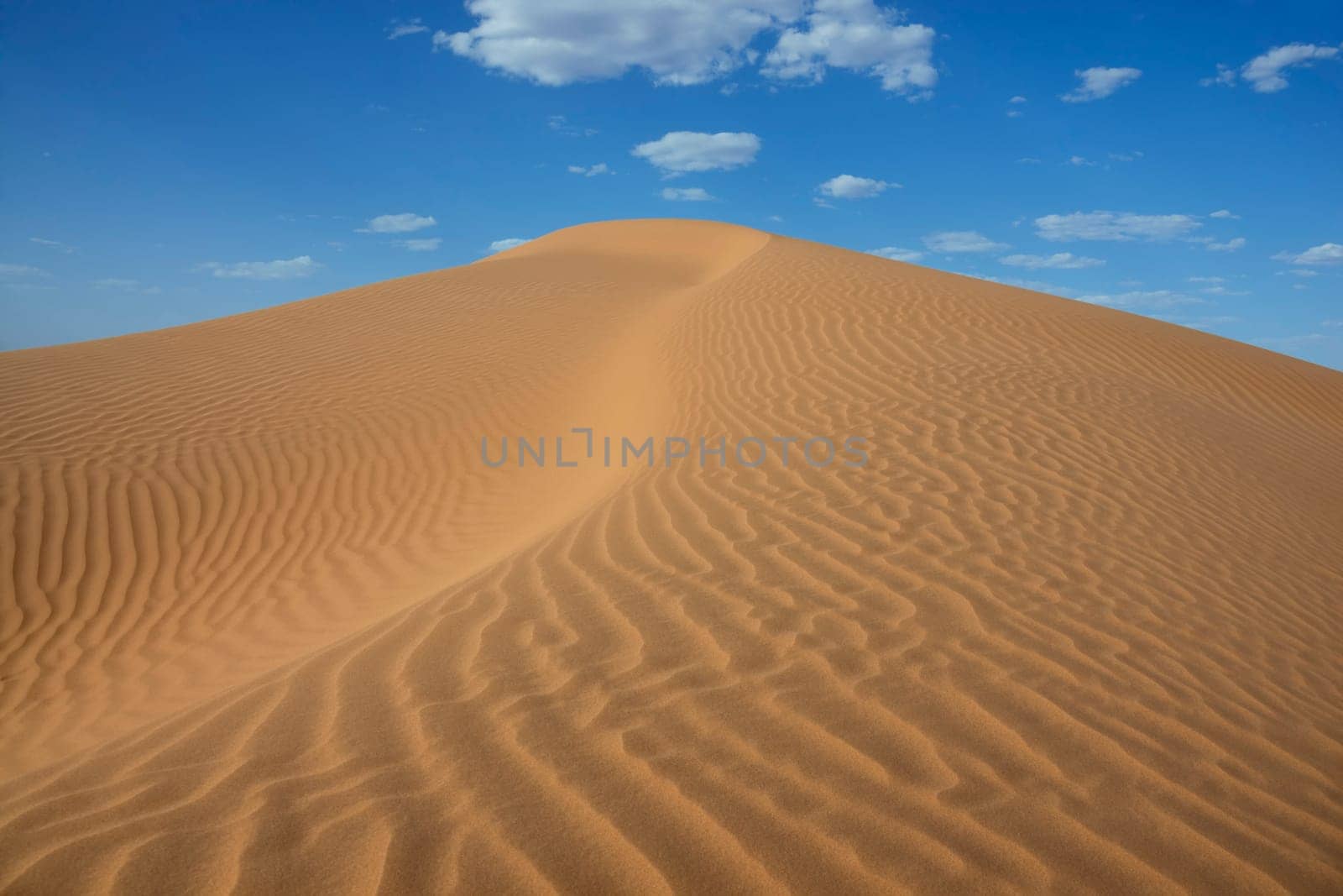 Sahara desert sand dune with cloudy blue sky at Erg Lihoudi, M&#039 hamid, Morocco