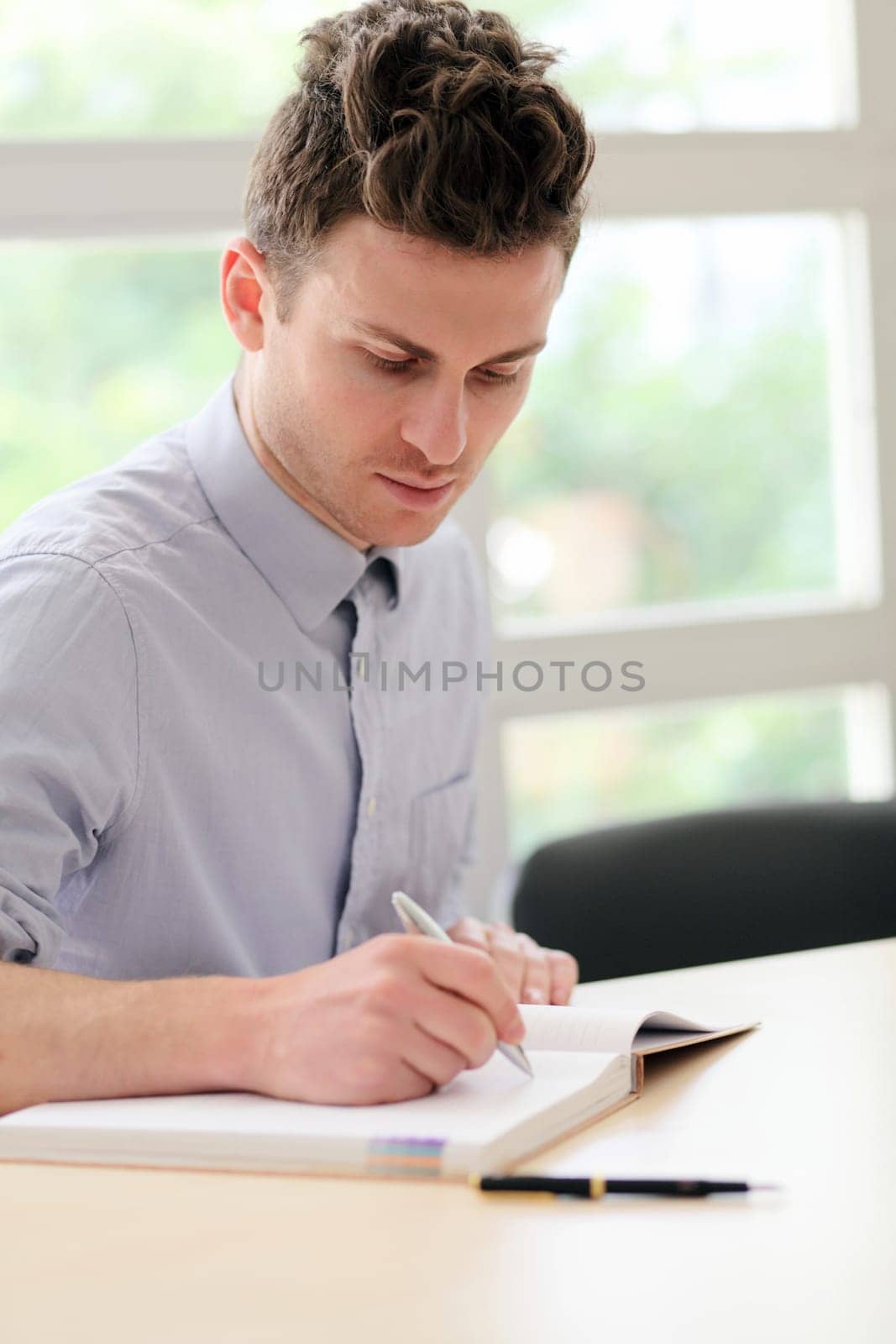 Young adult man writing notes with pen