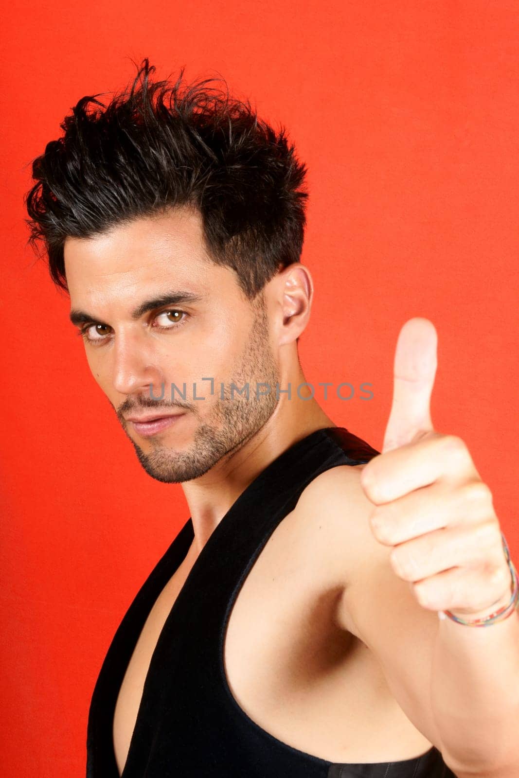 Smiling attractive 30 years old man with thumbs up over an orange background
