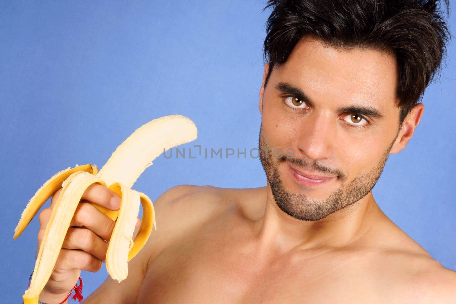 Smiling 30 years old man with banana over a blue background. With copy space.