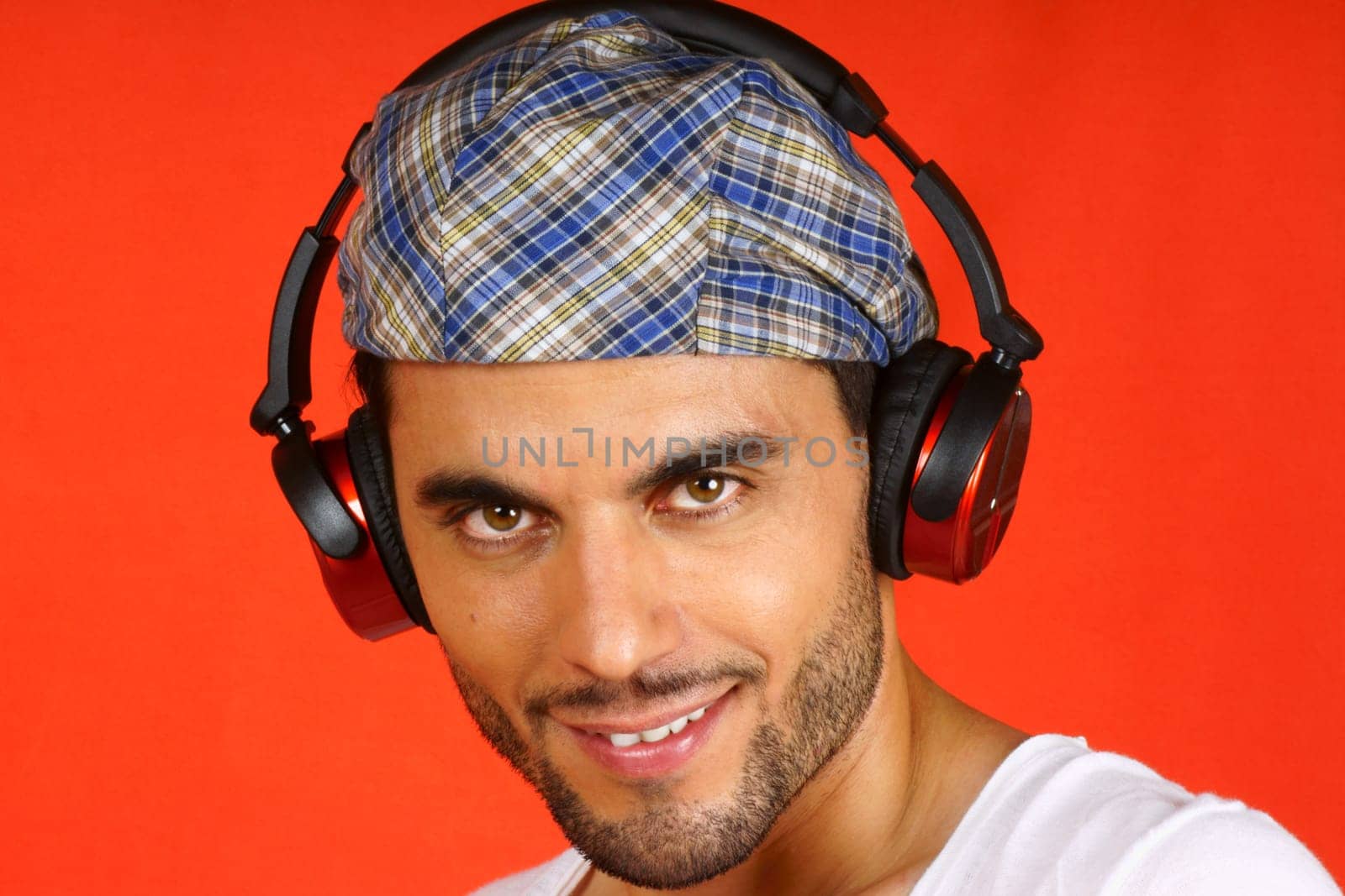 Smiling 30 years old man with beret and earphones over an orange background