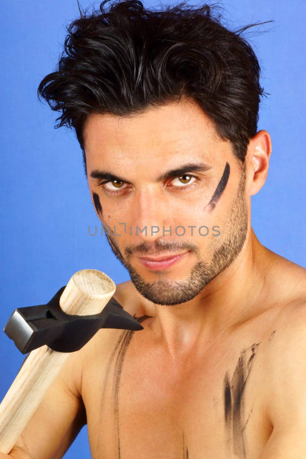 Dirty shirtless worker with hammer over a blue background