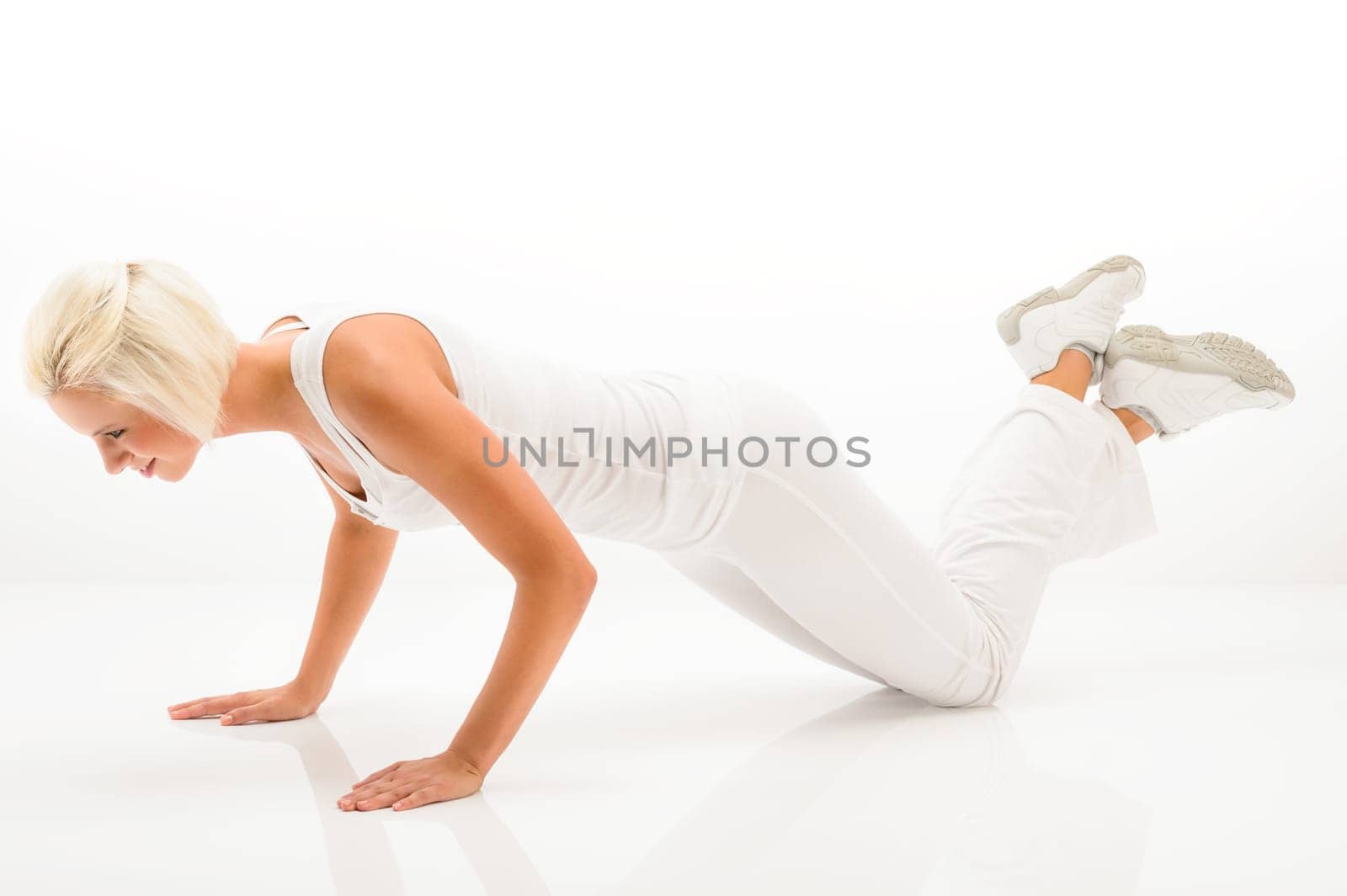 Young sportive woman doing pushups on white background