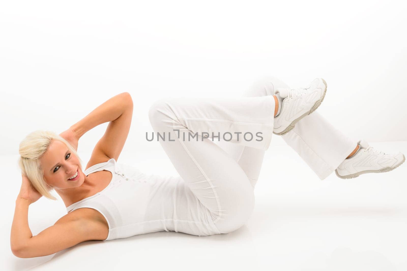 Young fitness woman exercise abs lying on white floor
