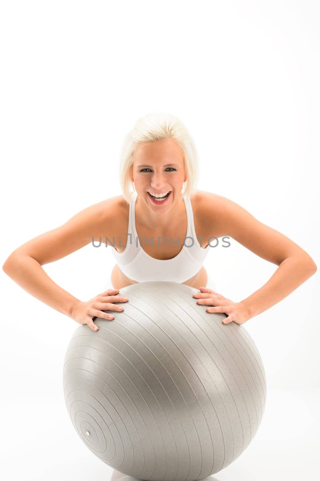 Smiling woman exercising on fitness ball on white background
