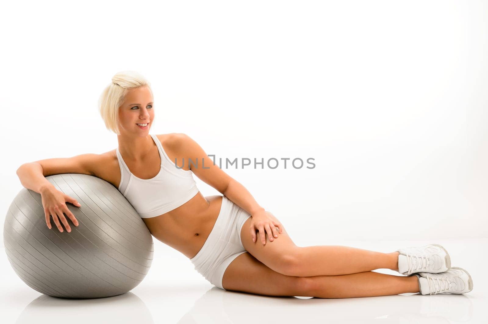 Sportive woman leaning on gym ball on white background