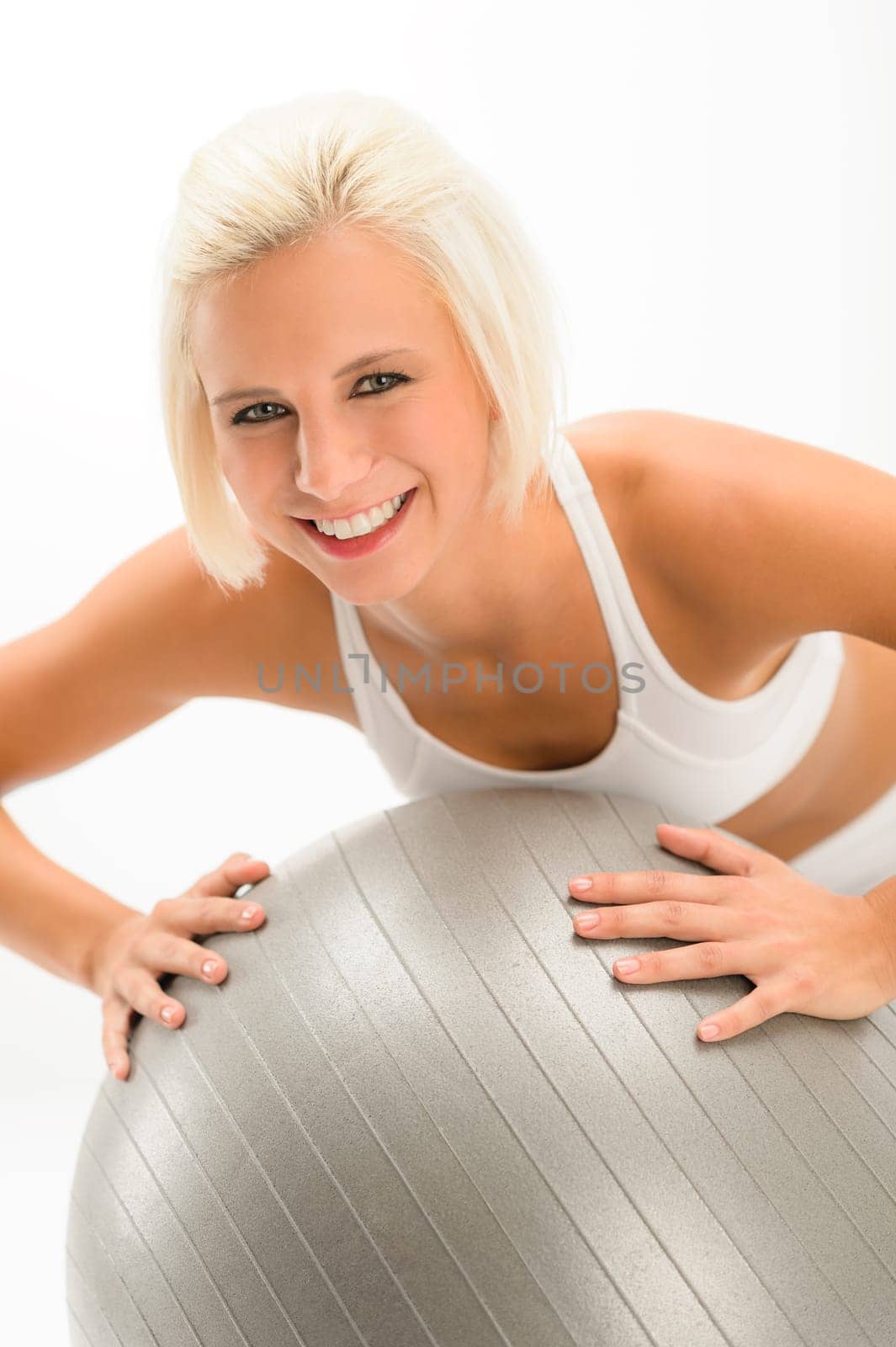 Smiling woman exercising on fitness ball on white background