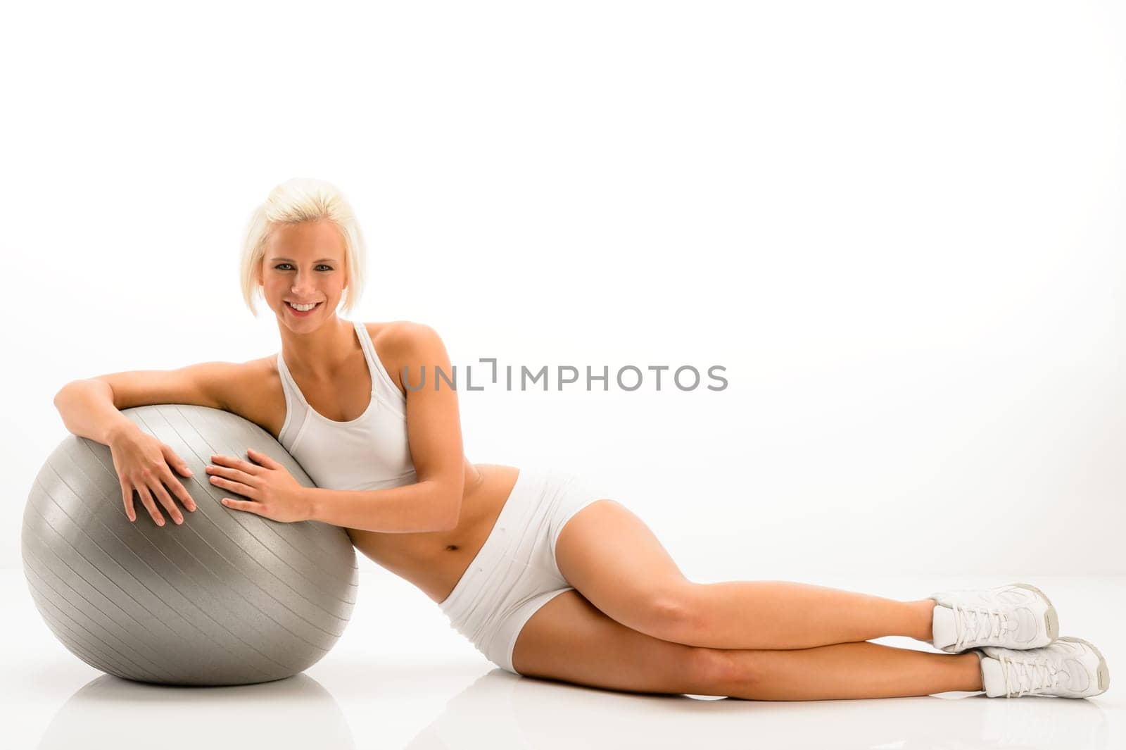 Sportive woman leaning on gym ball on white background