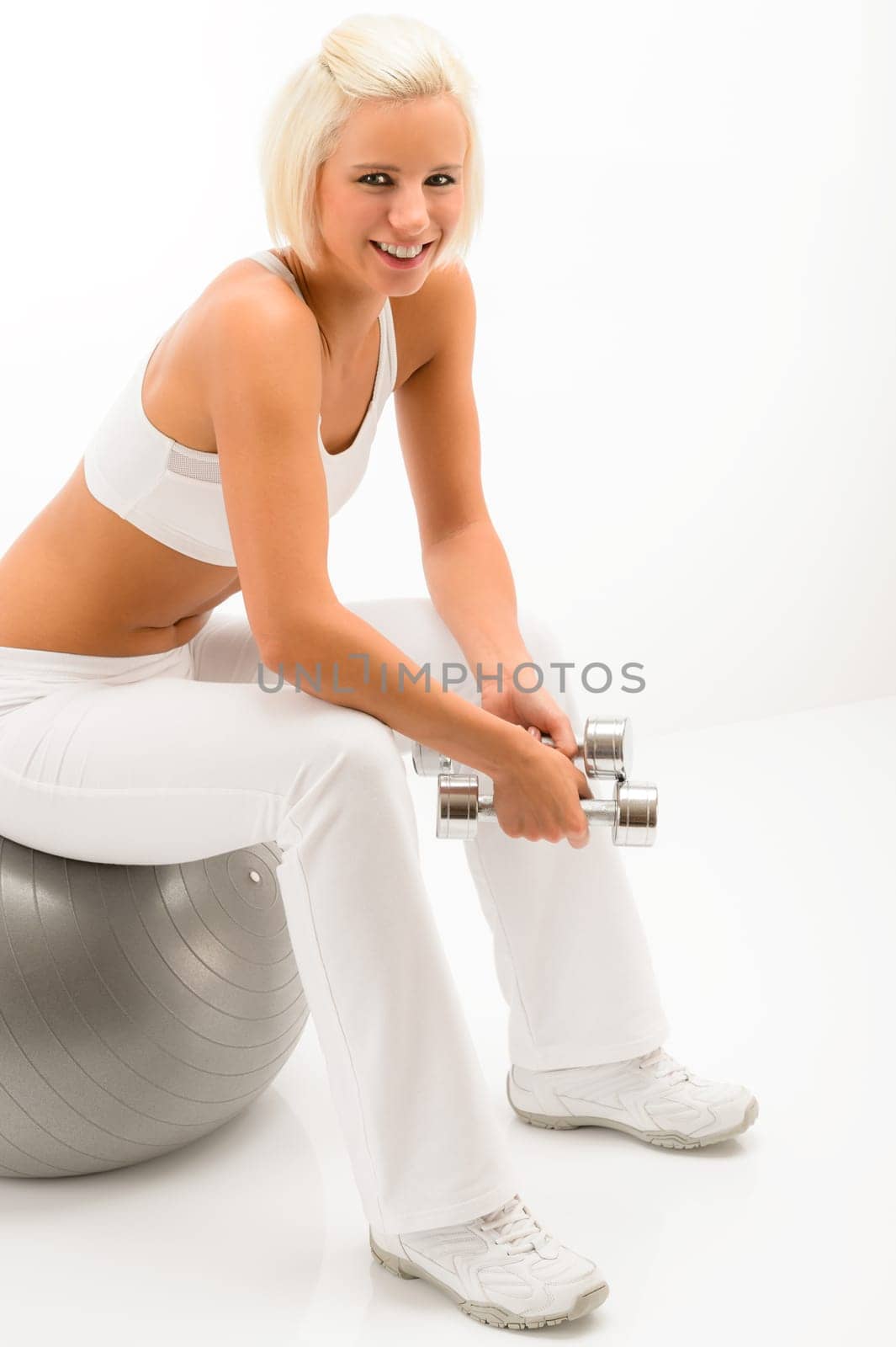 Smiling sport woman sitting on fitness ball hold dumbbells