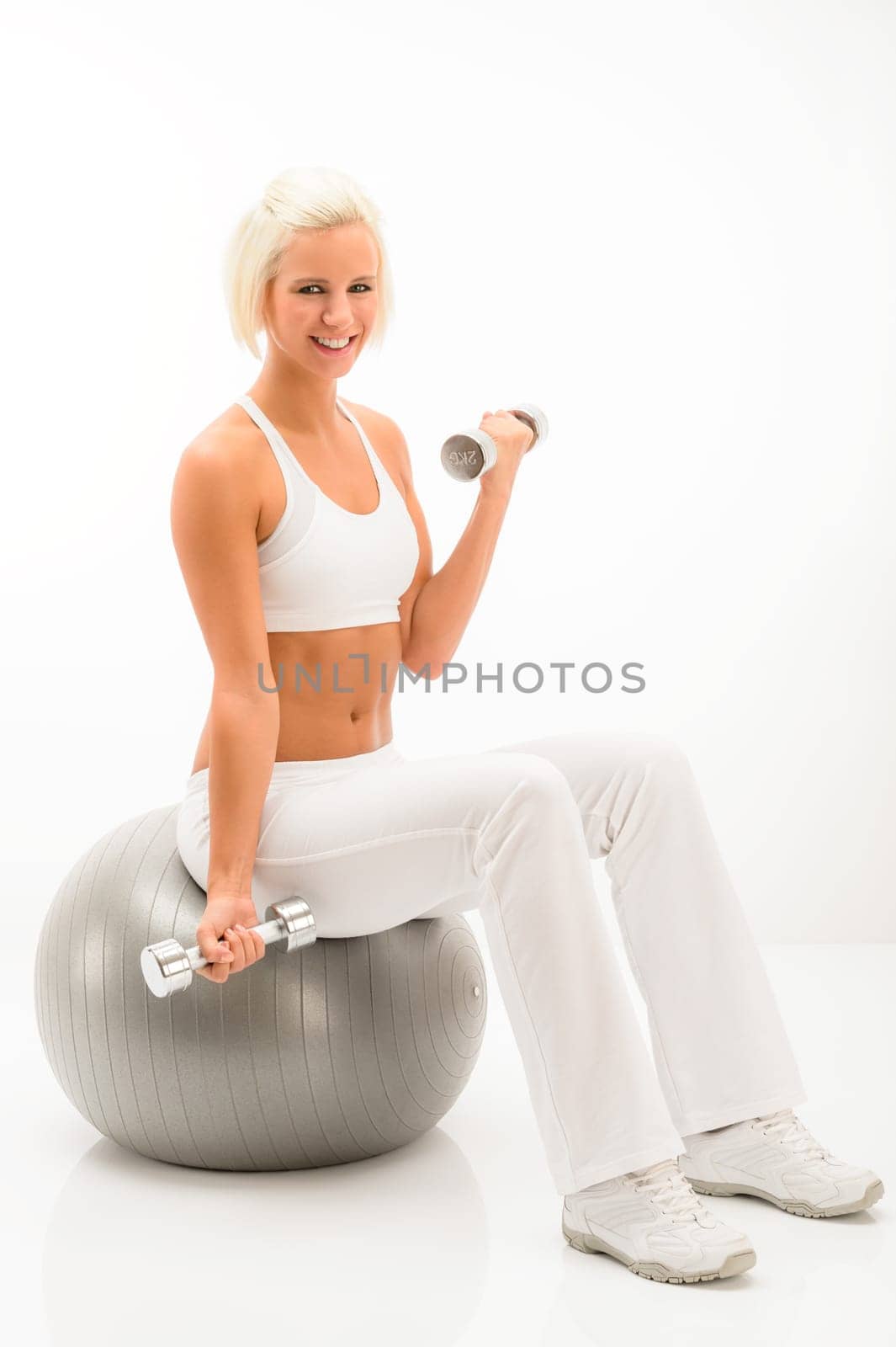 Woman doing weight training sitting fitness ball on white background