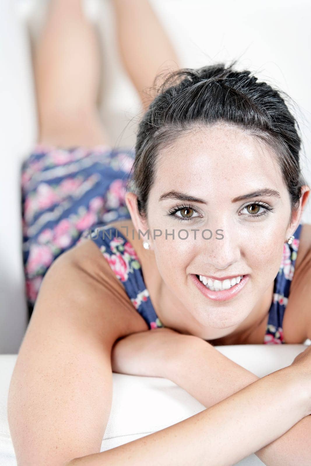 Beautiful young woman wearing a blue summer dress resting on her sofa at home