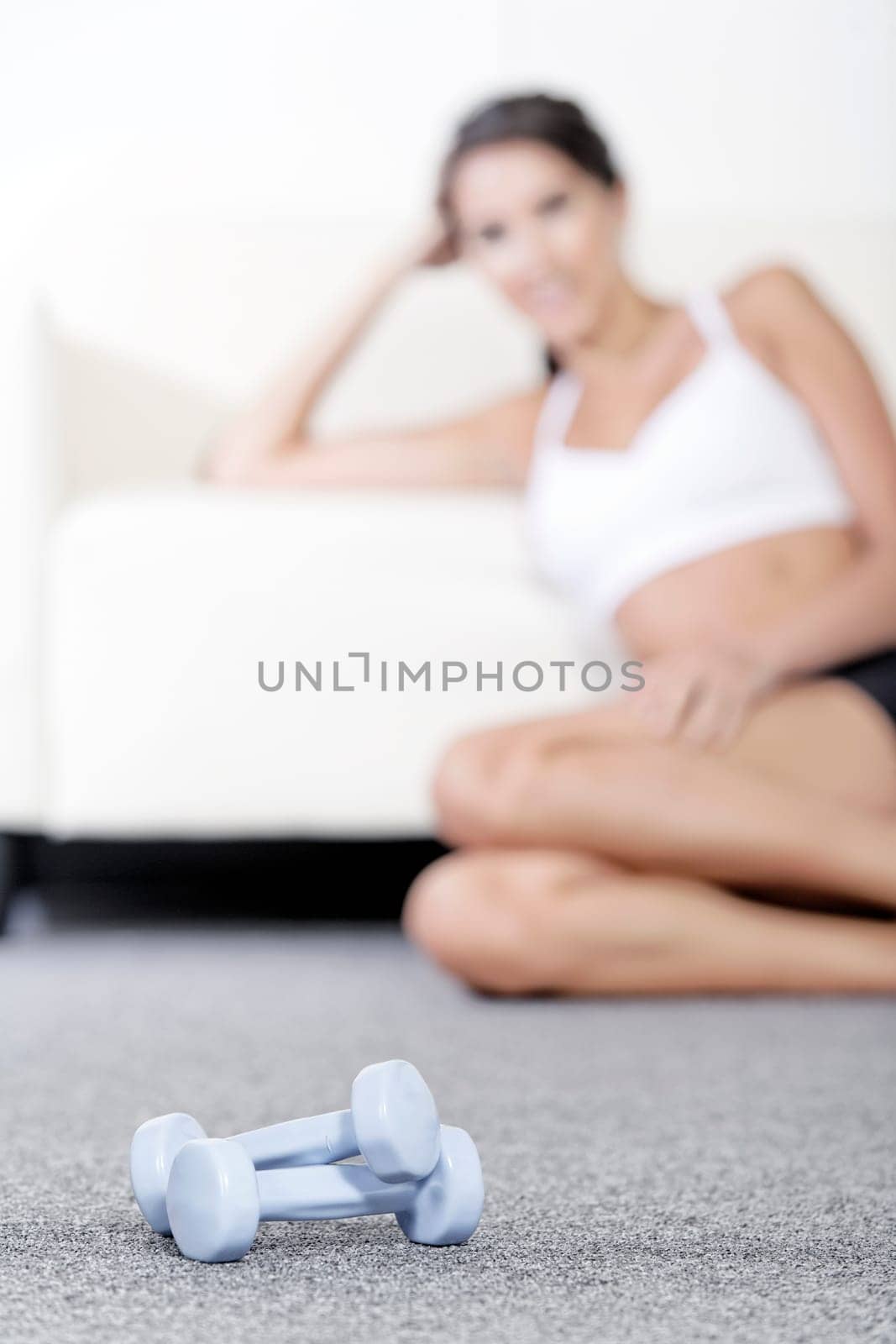 Beautiful young woman training with weights at home