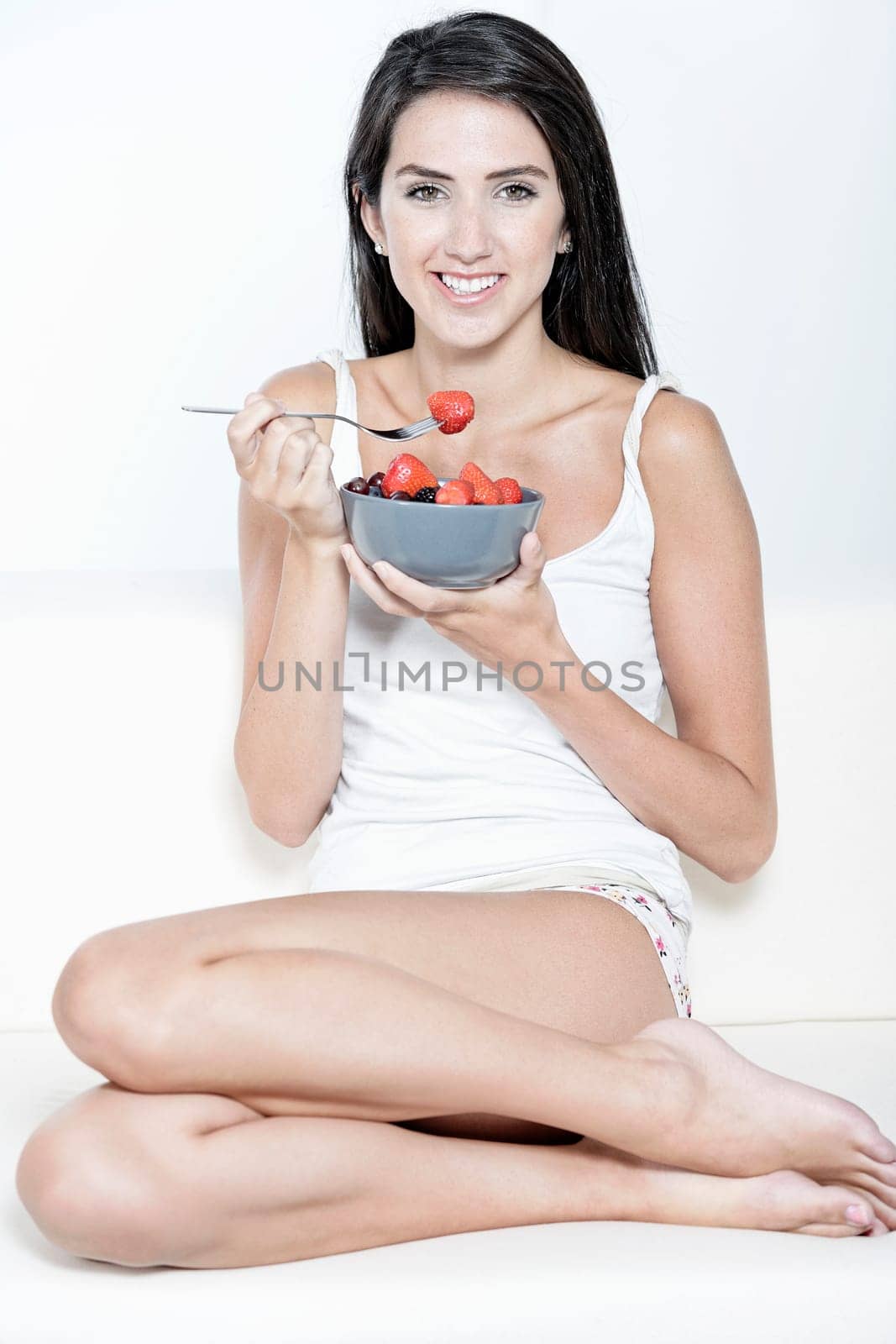 Beautiful young woman enjoying fresh fruit for breakfast at home