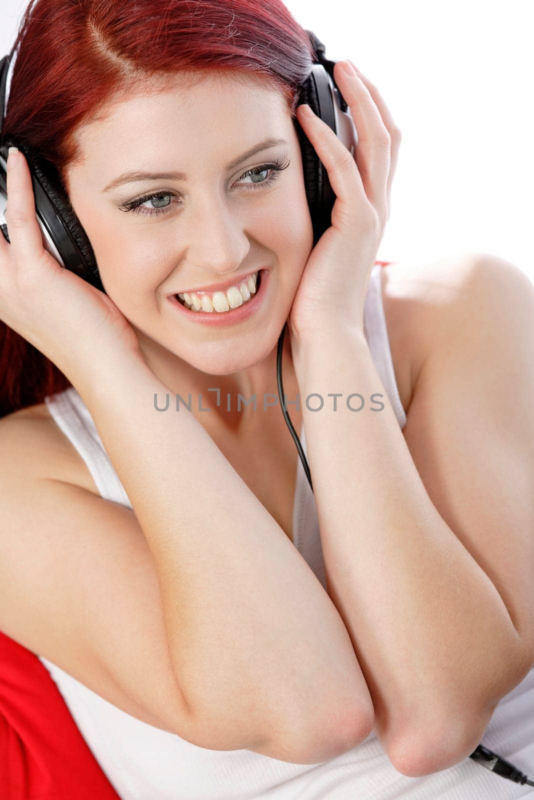Happy smiling young woman listening to music at home on headphones