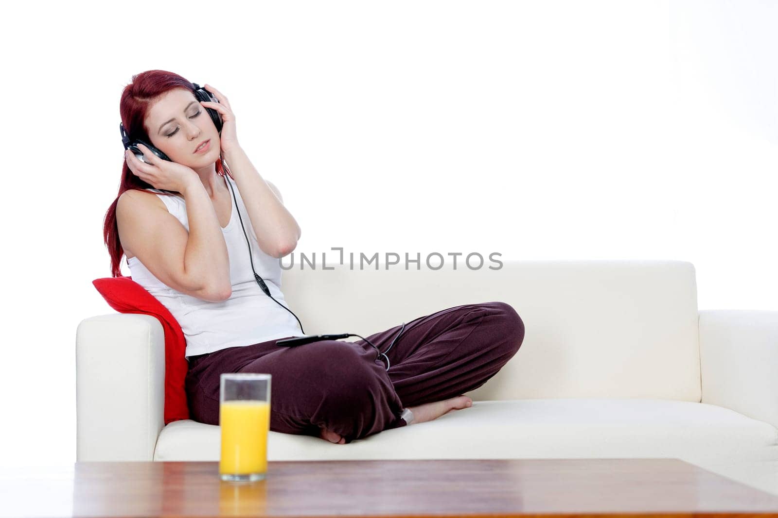 Happy smiling young woman listening to music at home on headphones