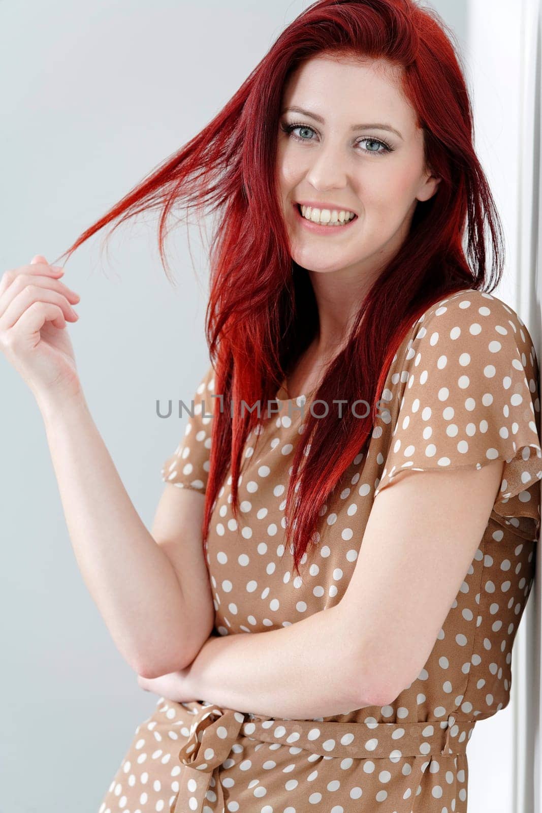 Beautiful happy young woman in a summer dress leaning against a wall.