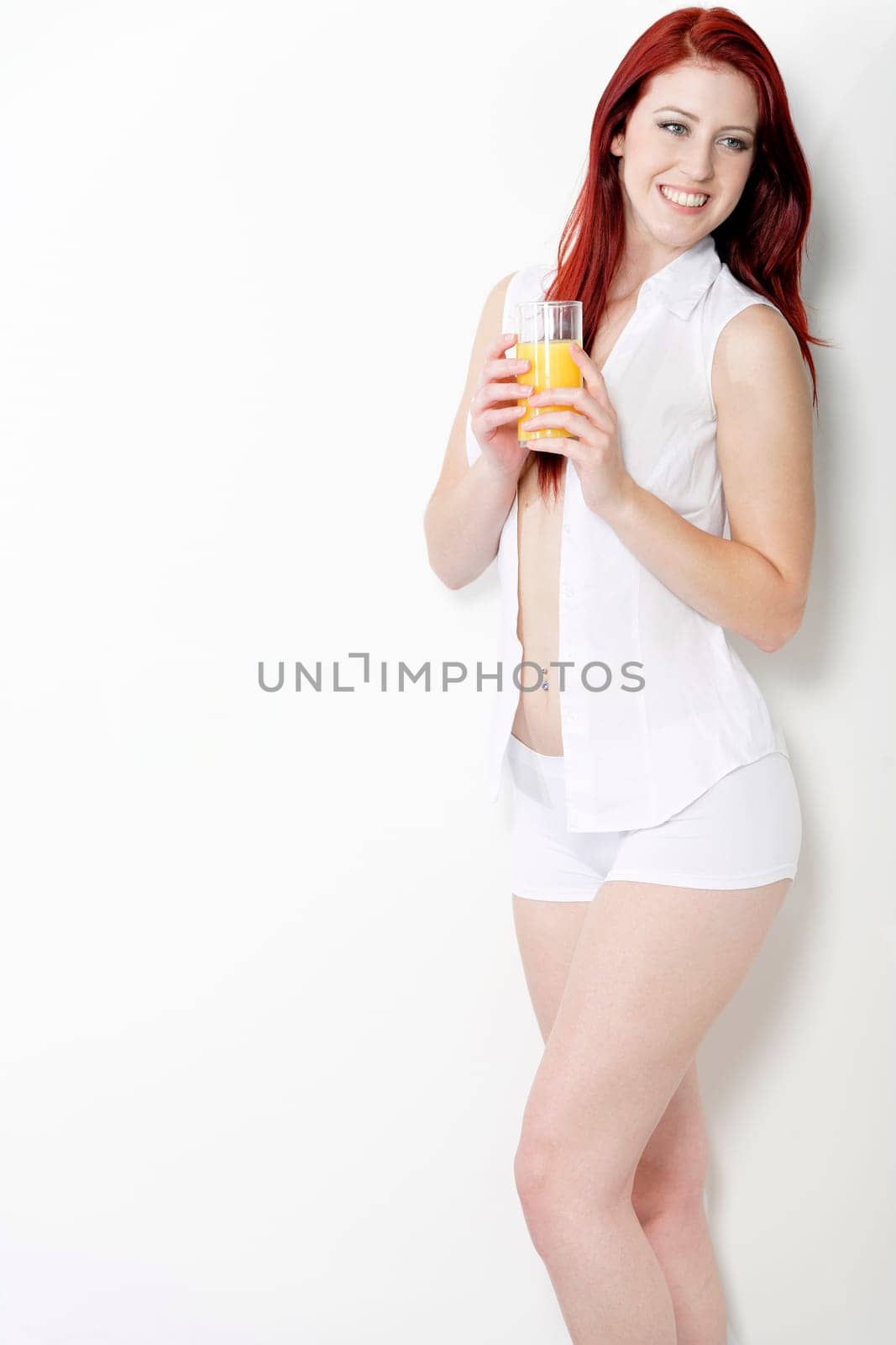 Beautiful young woman in white shirt and underwear enjoying some breakfast Orange juice.