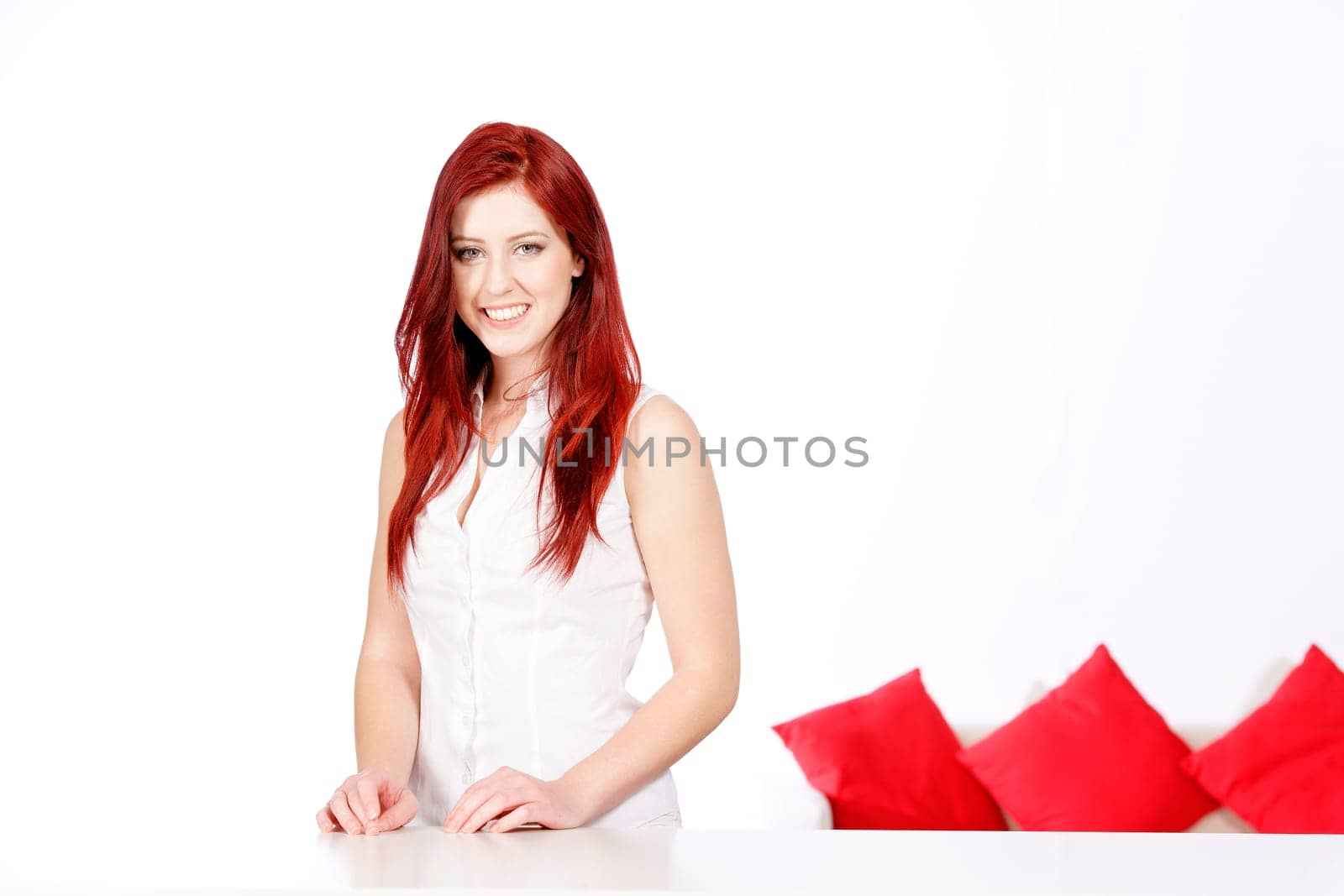 Beautiful young woman leaning on a table at home with a sofa in the background.