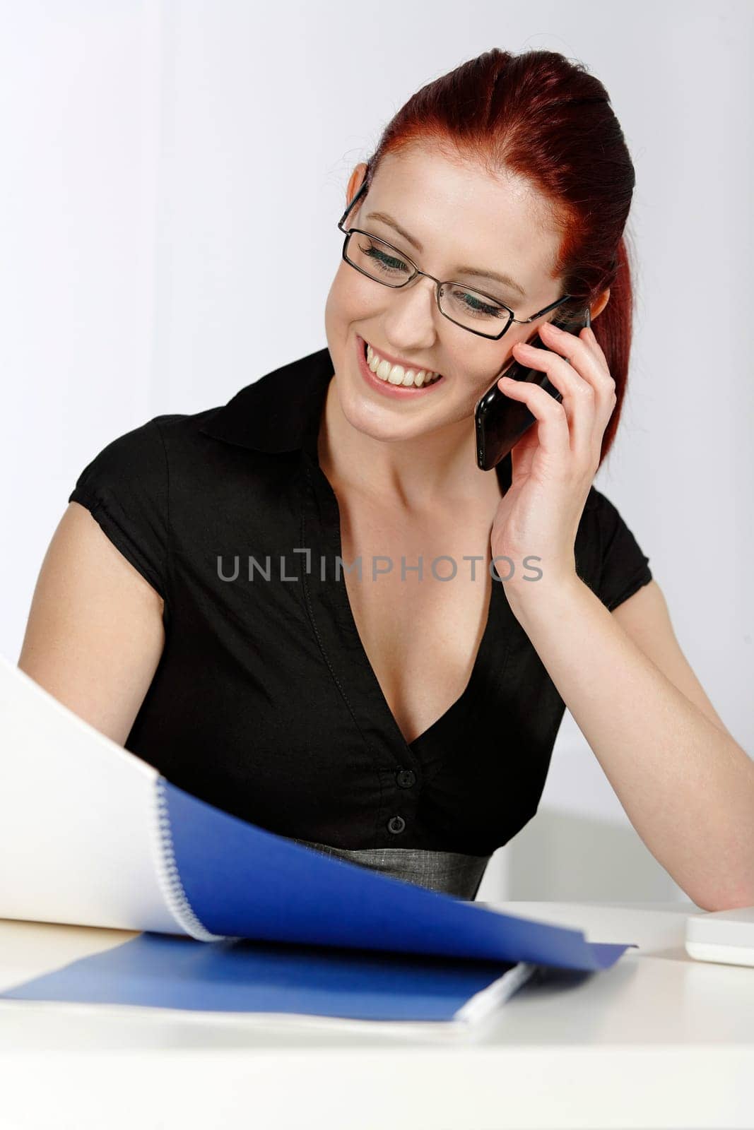 Beautiful young woman talking on her mobile phone at work