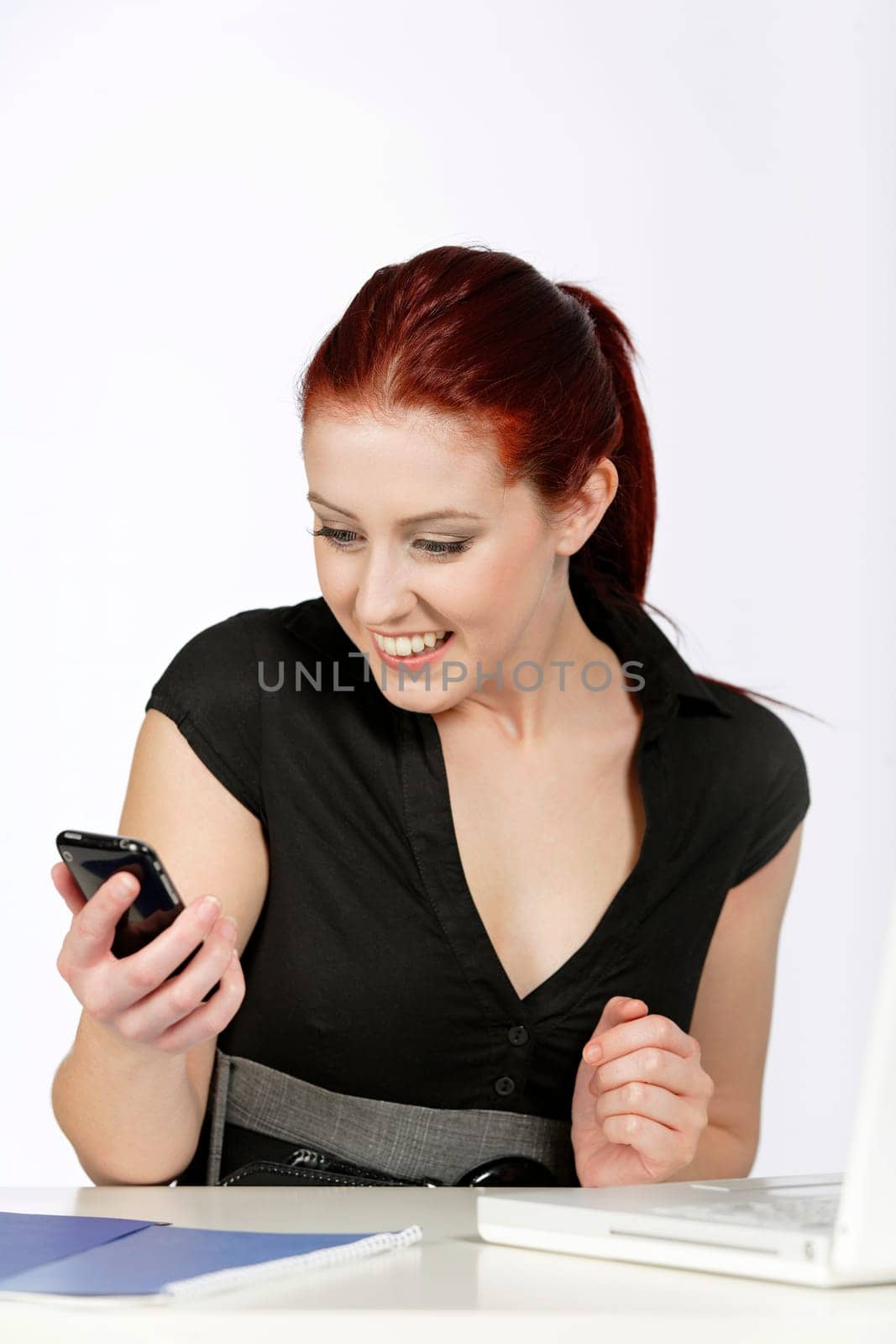 Professional young woman receiving good news on her mobile at work