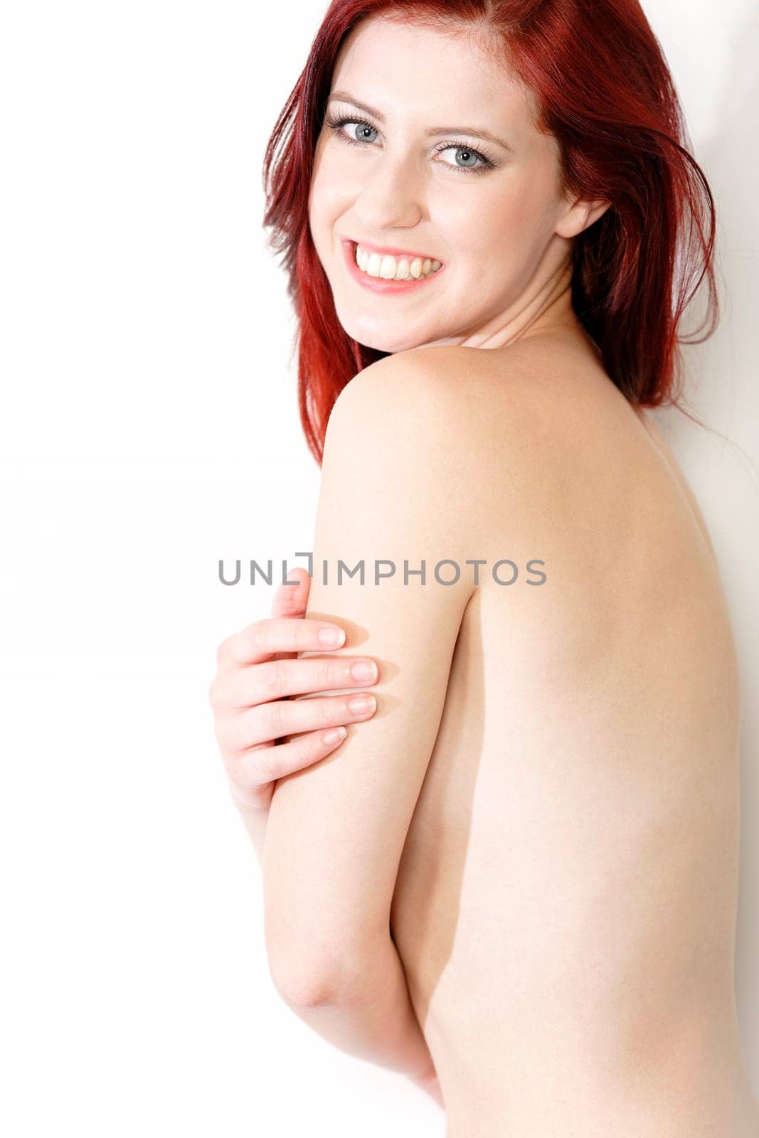 Beautiful young woman in white underwear covering her chest and smiling