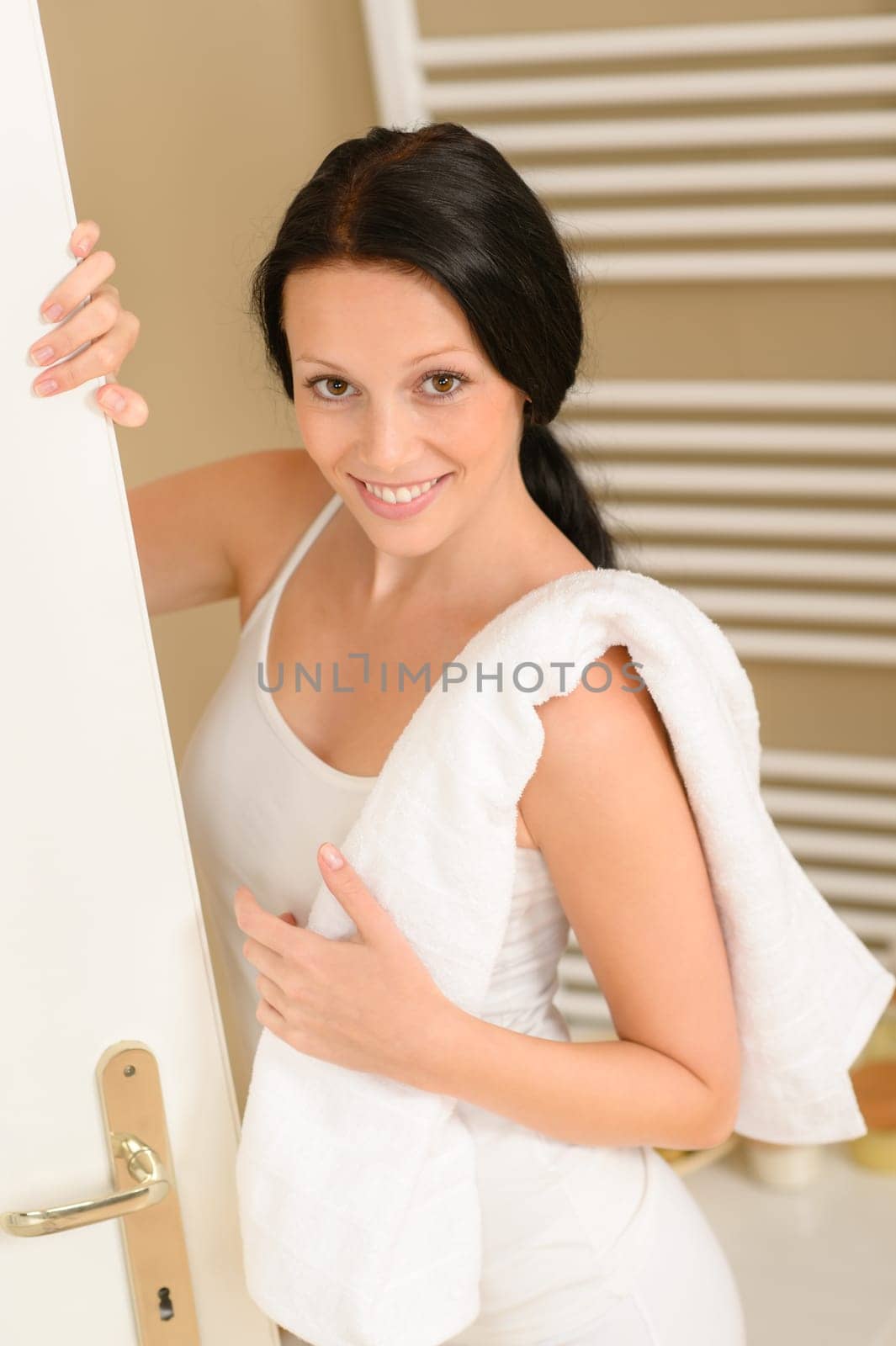 Beautiful woman in bathroom with towel smiling looking at camera