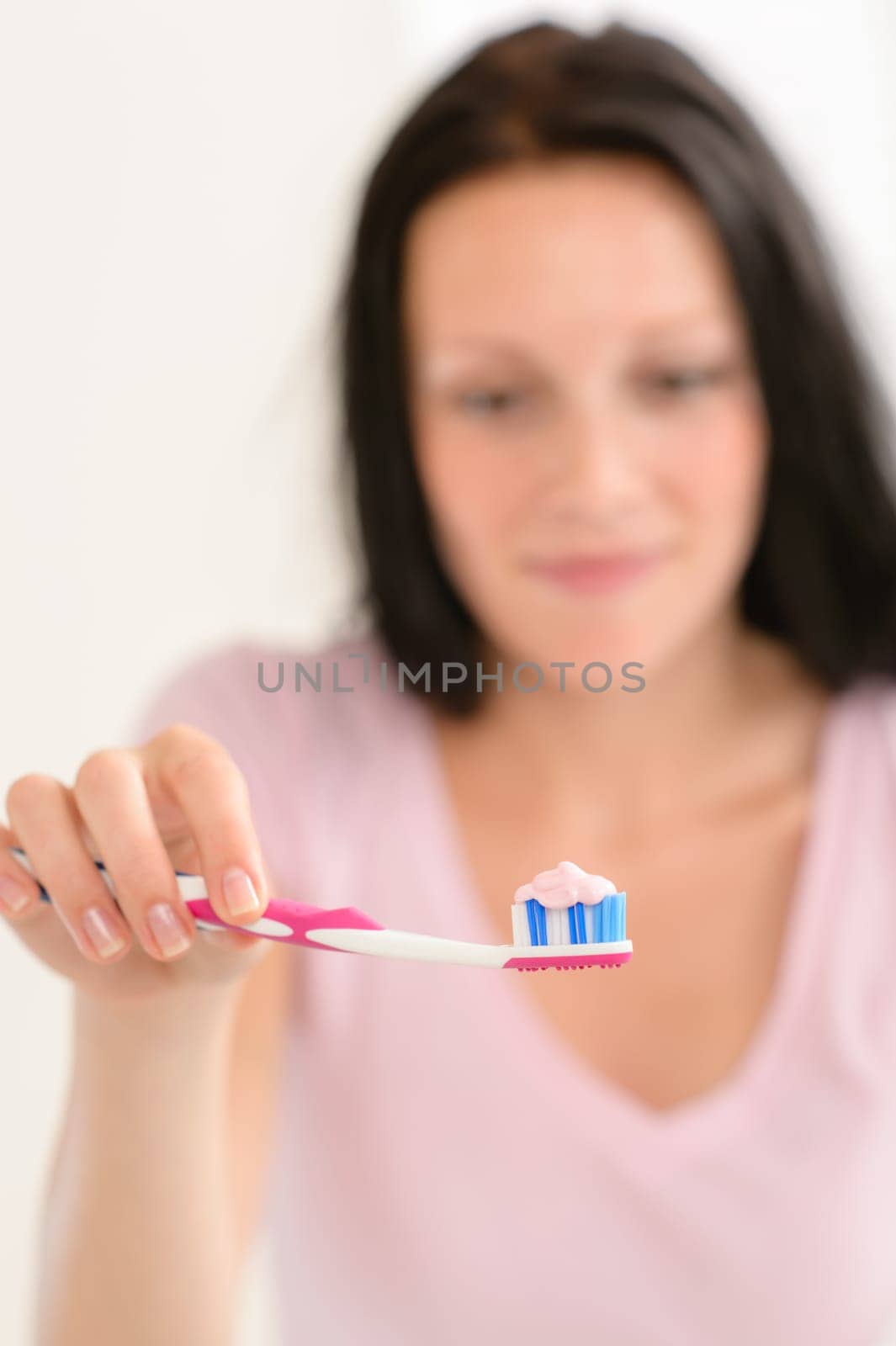 Close-up toothbrush with toothpaste with background woman before teeth brushing