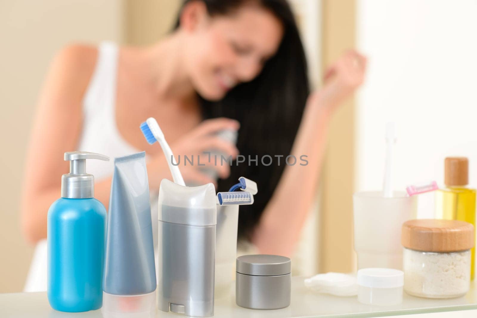 Bathroom shelf with beauty and hygiene products woman in background