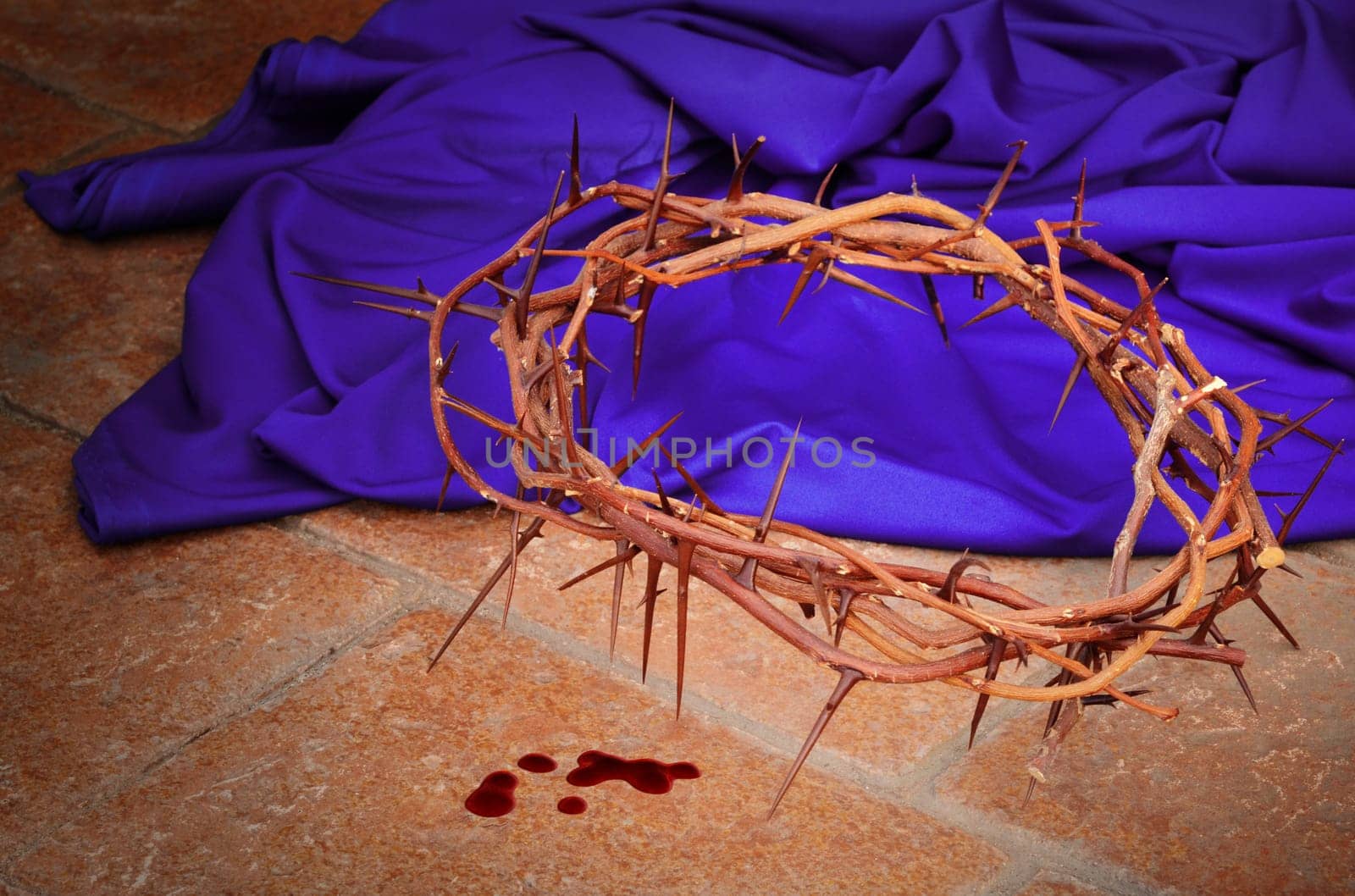 Crown of thorns as worn by Christ during the crucifixion against a purple robe and pavement tiles