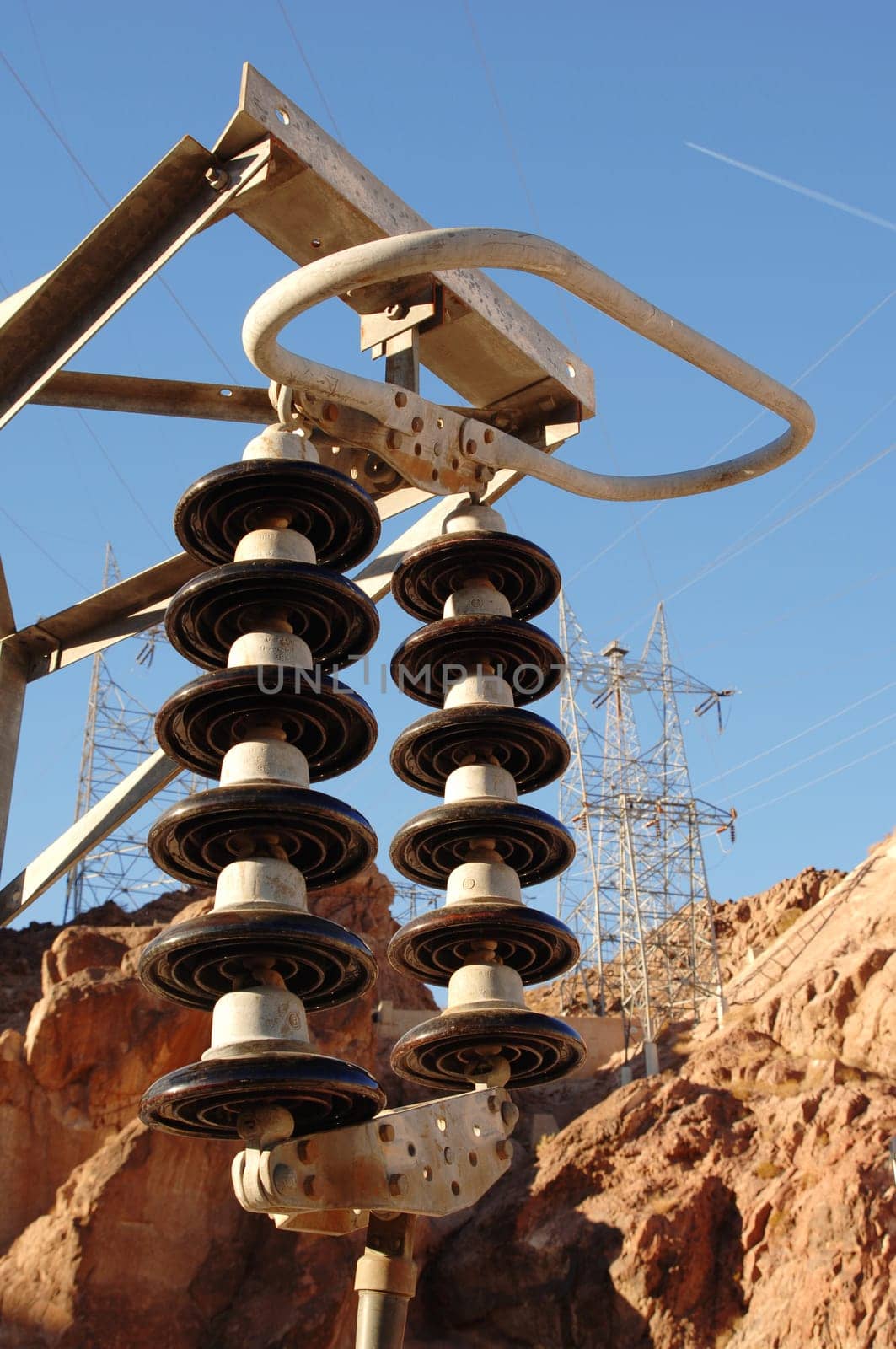High voltage electrical insulator with transmission towers in the background