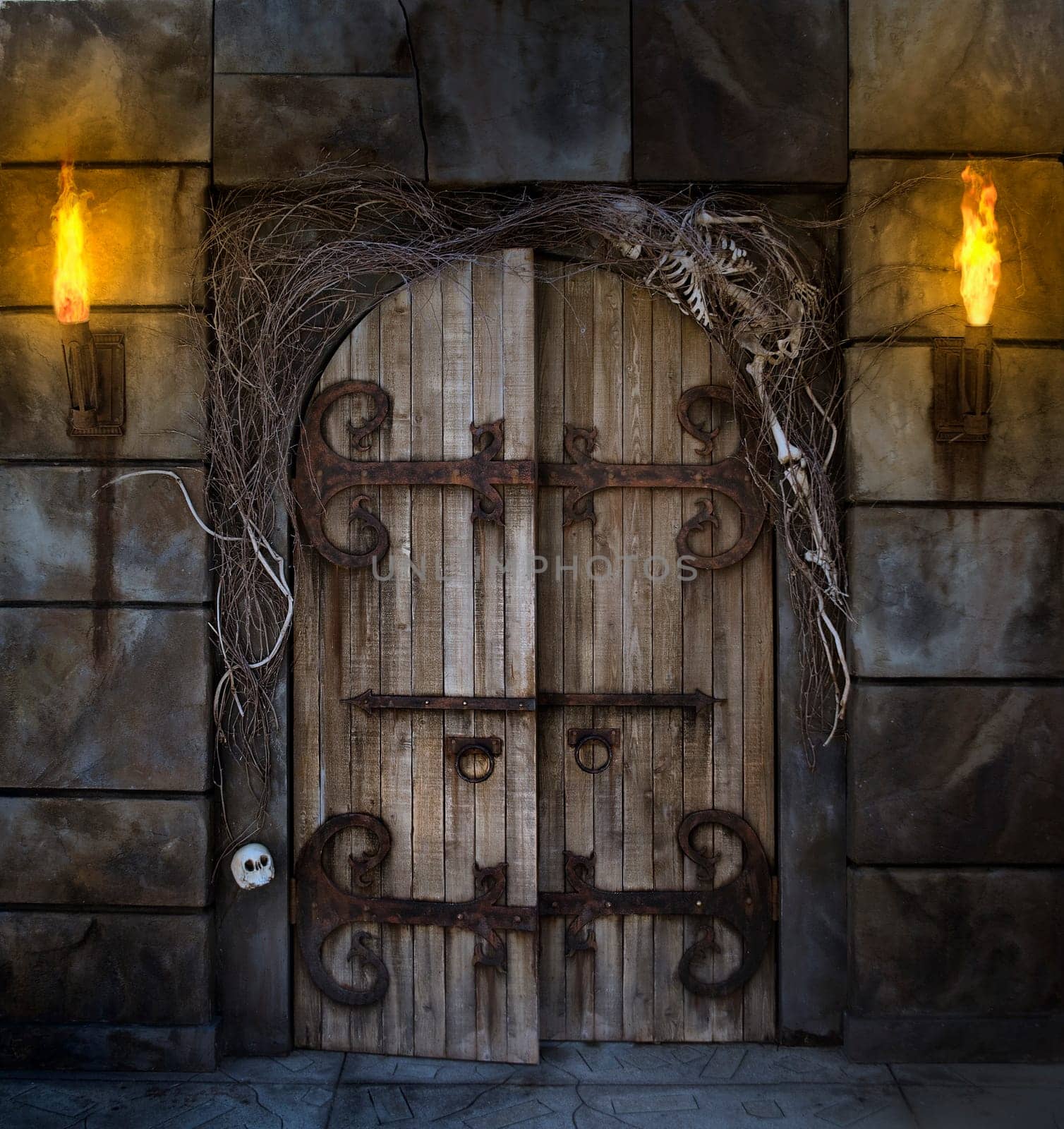 Spooky dungeon door flanked with two flaming torches and decorated with twigs and skeleton bones