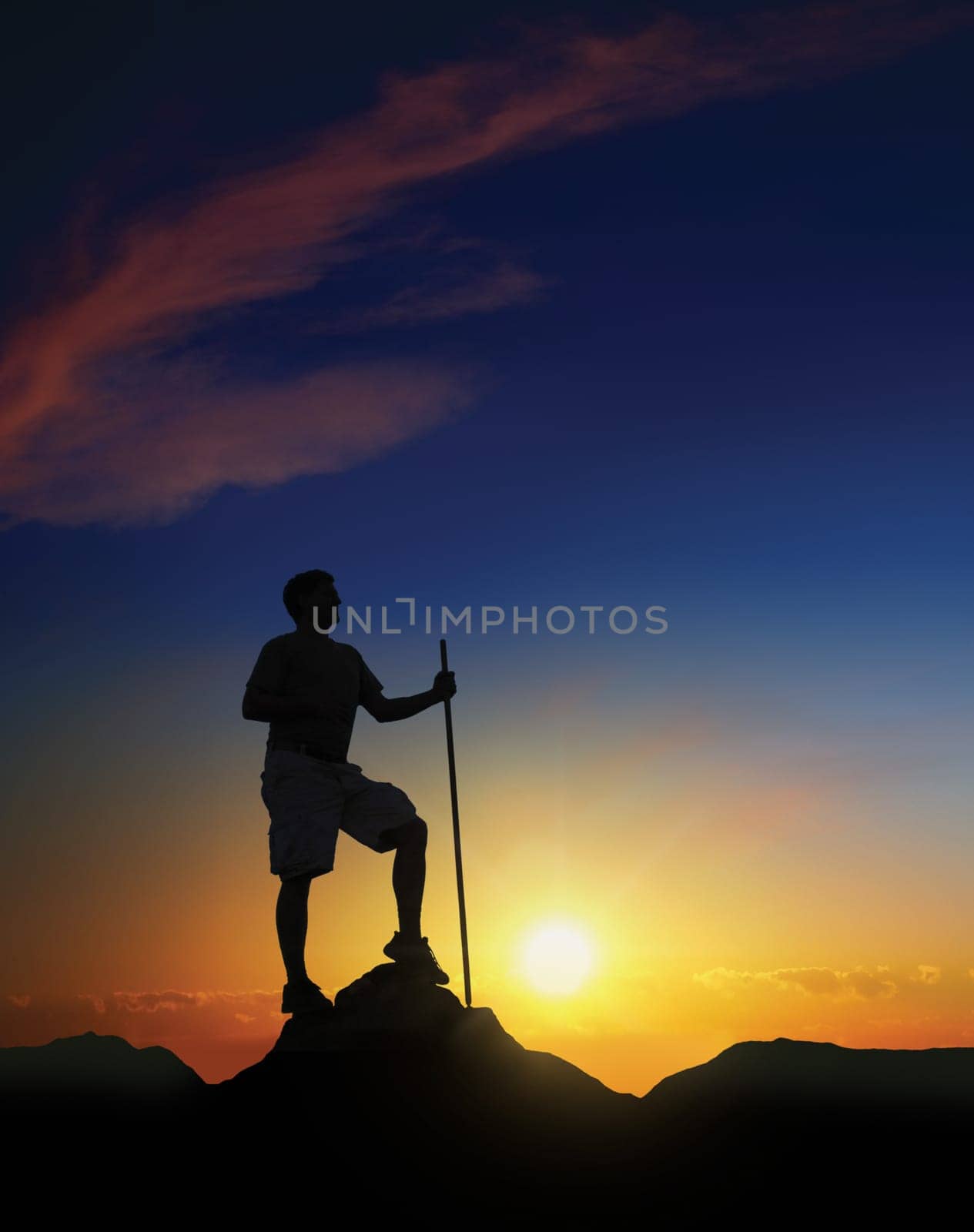 Hiker at the summit of a mountain with the sun rising in the background