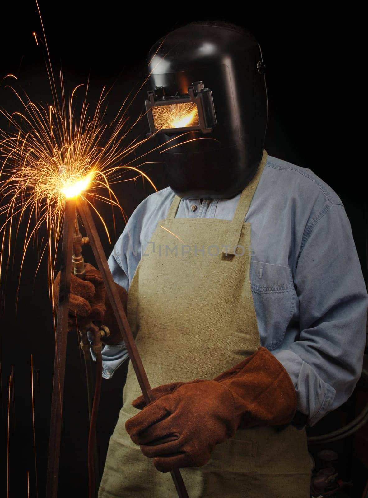 Welder torching a piece of steel against a black background