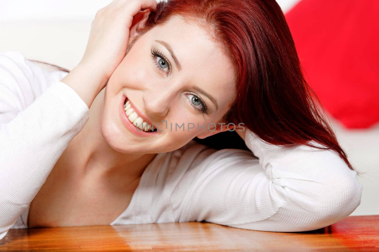 Beautiful young woman resting on a coffee table in front of sofa at home.