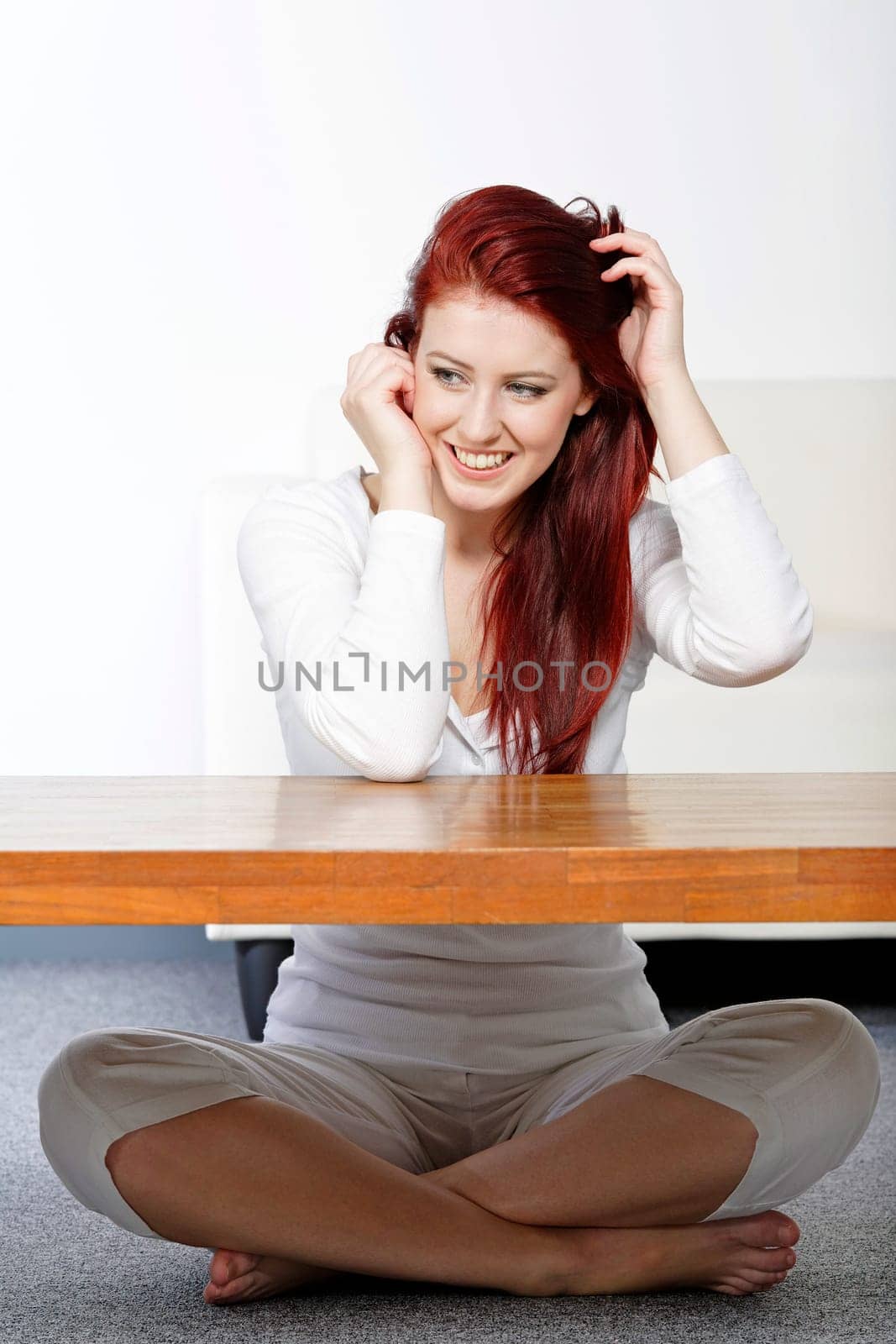 Beautiful young woman resting on a coffee table in front of sofa at home.