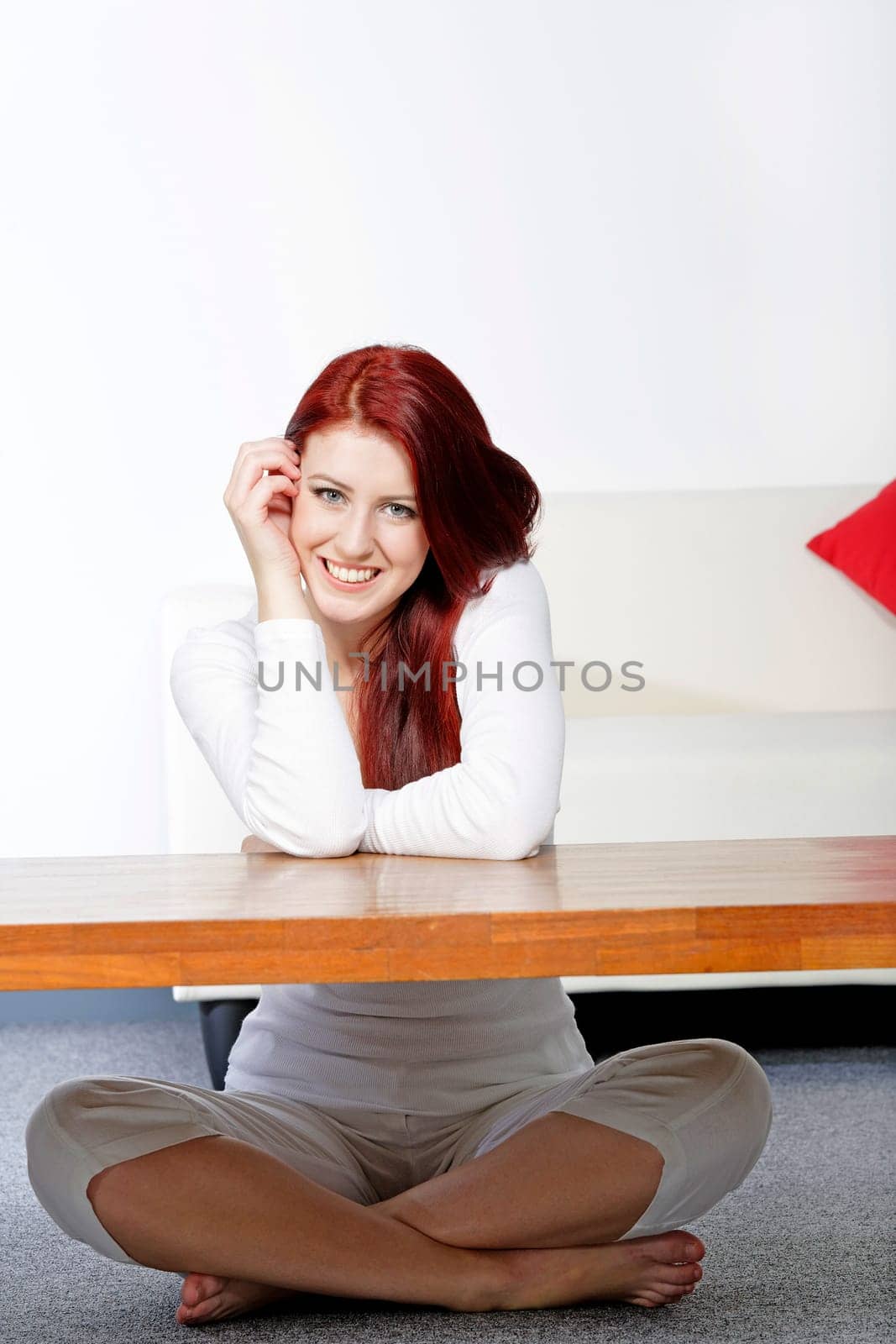 Beautiful young woman resting on a coffee table in front of sofa at home.