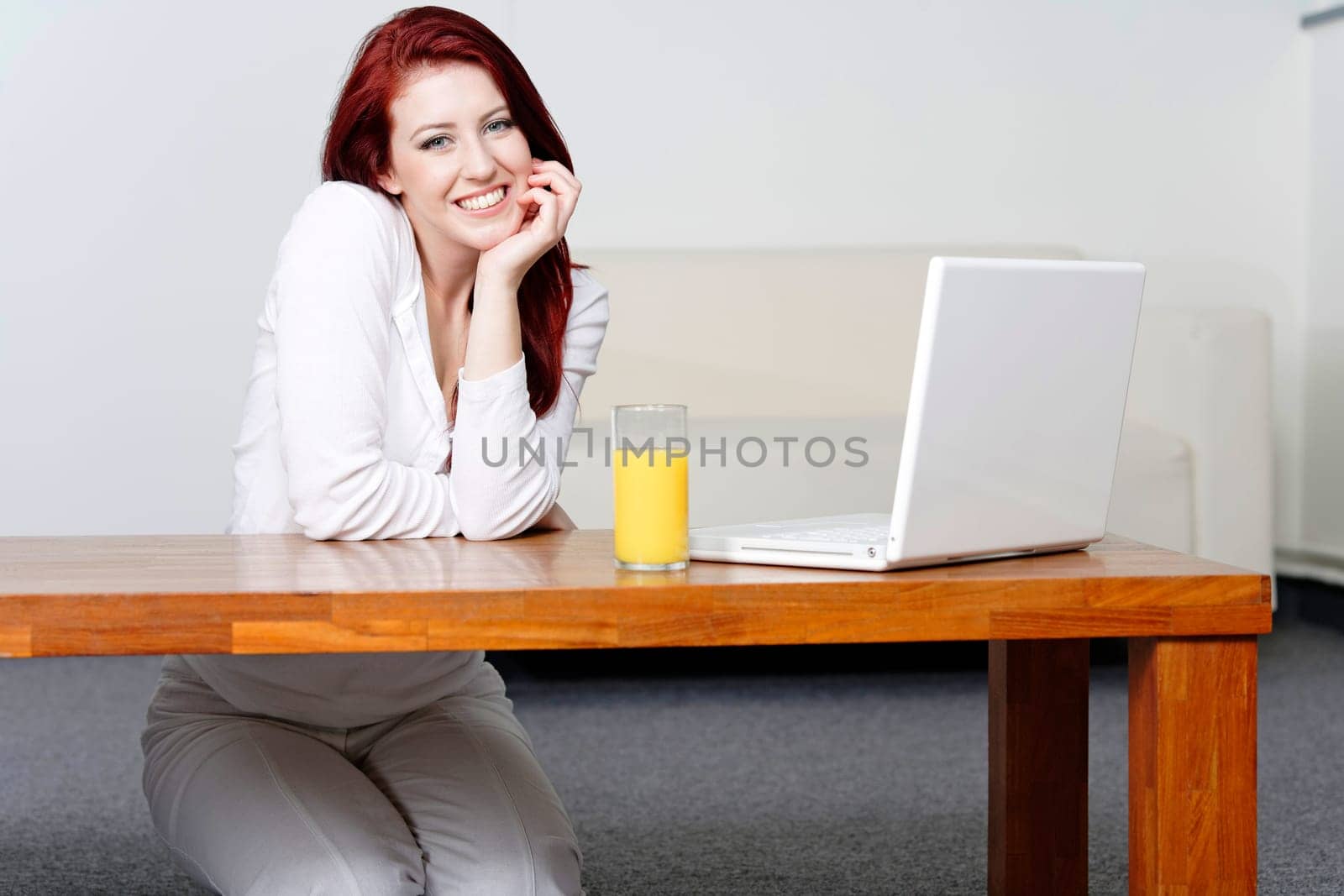 Beautiful young woman using a laptop at home with a fresh glass of Orange juice.